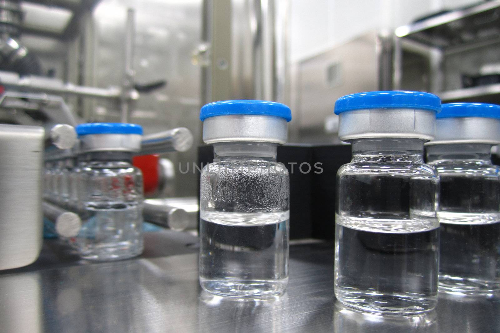 Bottles in the processing machine in a pharmaceutical plant by Nickondr