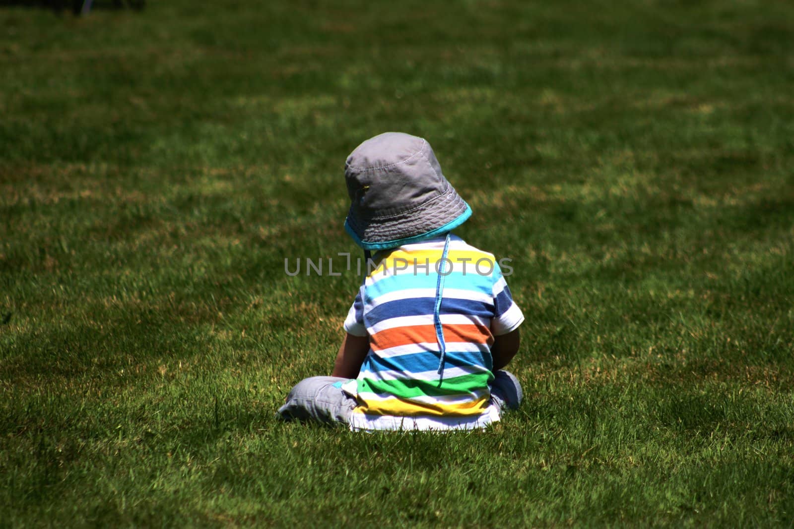 Toddler enjoying the sun while sitting in the grass