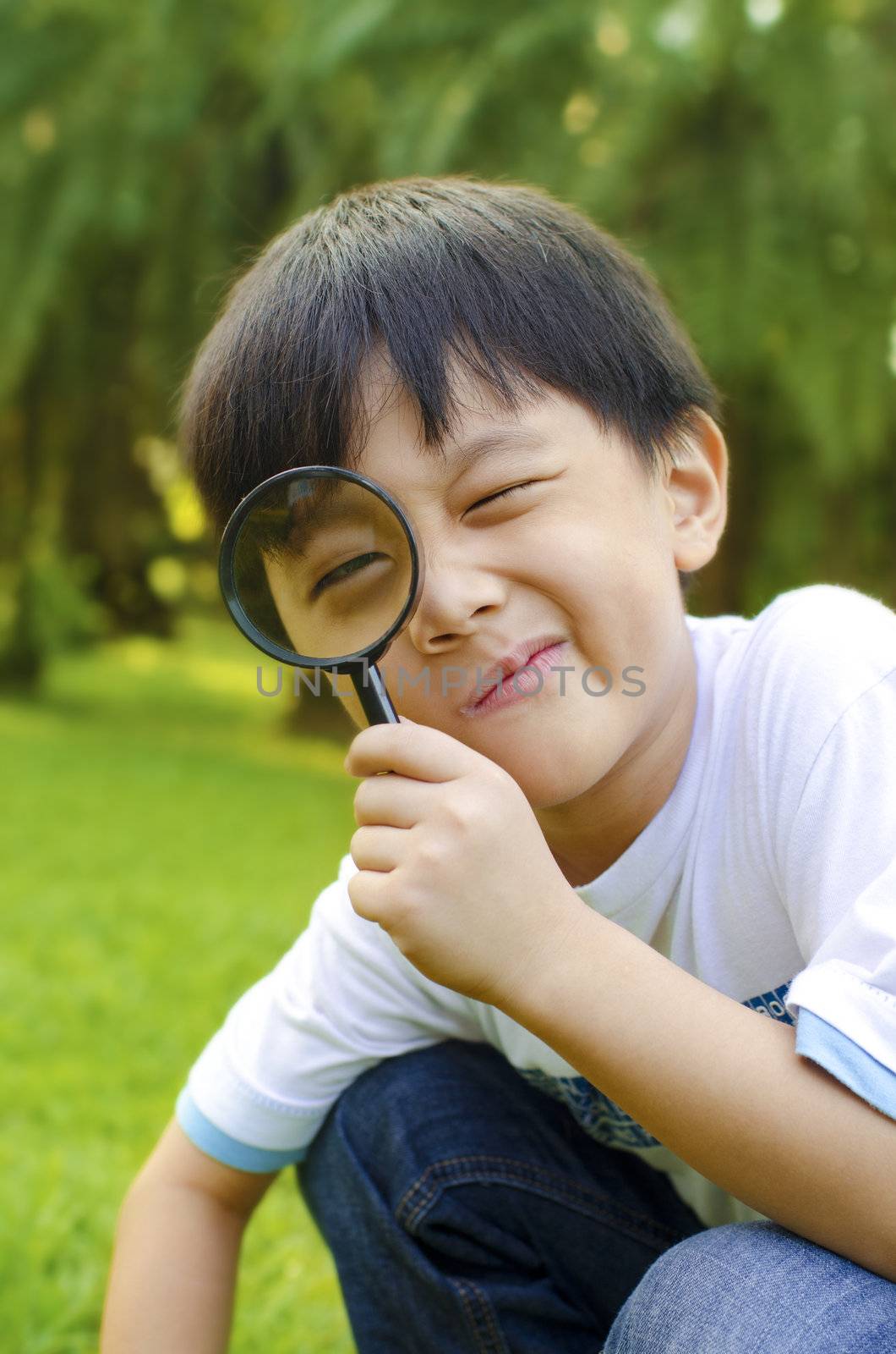 Little boy exploring nature by magnifier