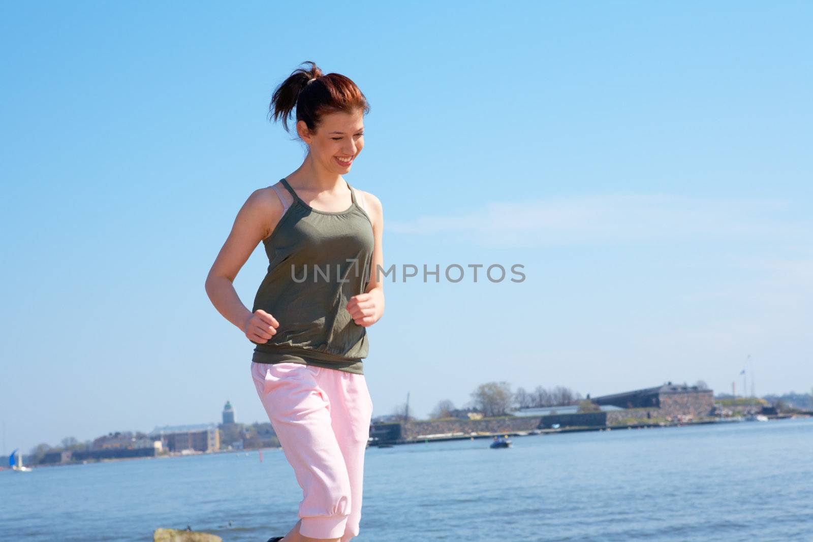 Teenage girl jogging by sea smiling