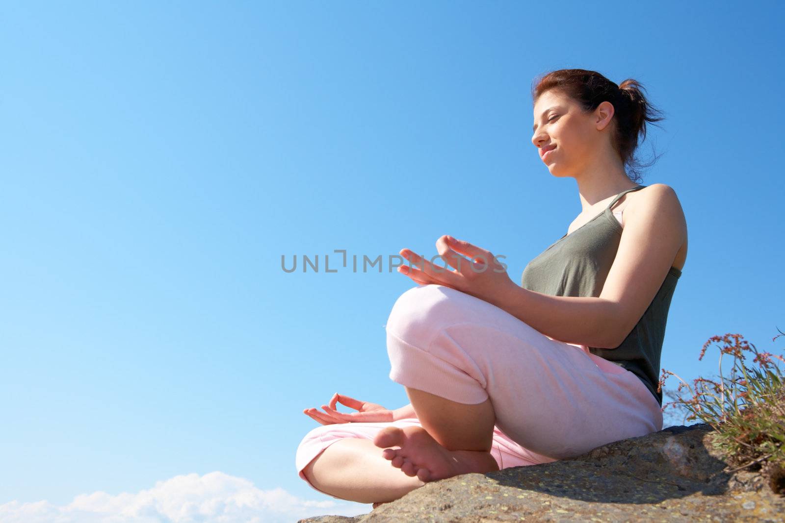 Teenage girl meditating bare feet on rock eyes closed