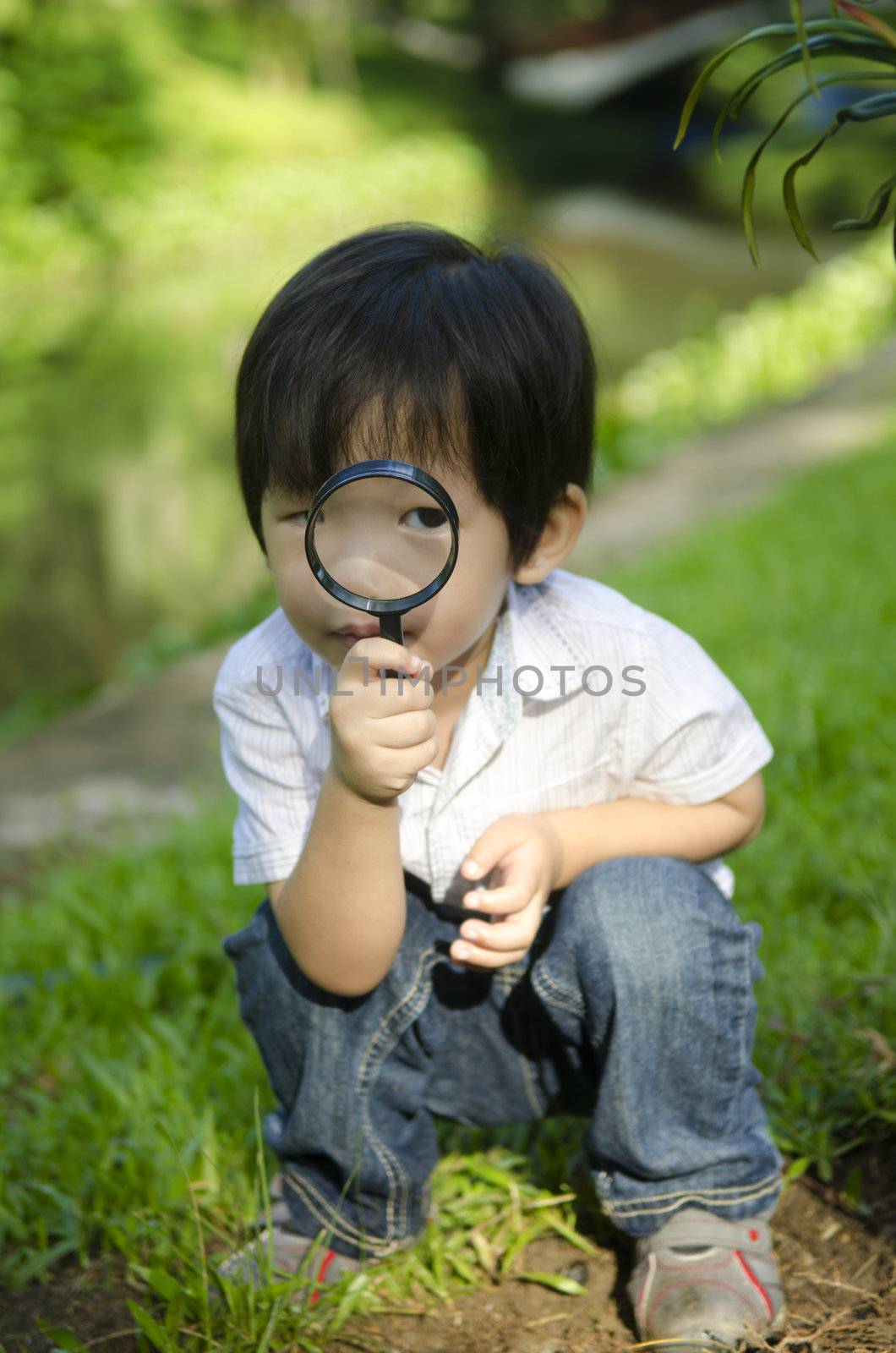 Little boy exploring nature by magnifier