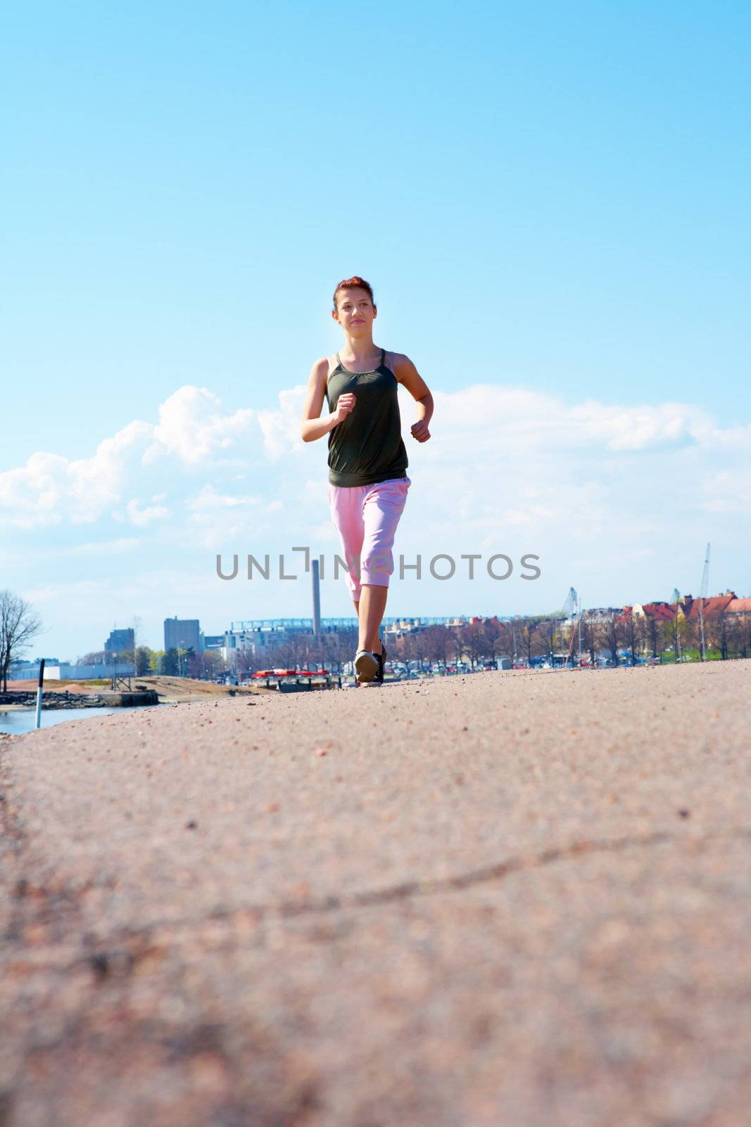 Teenage girl jogging on side walk in city