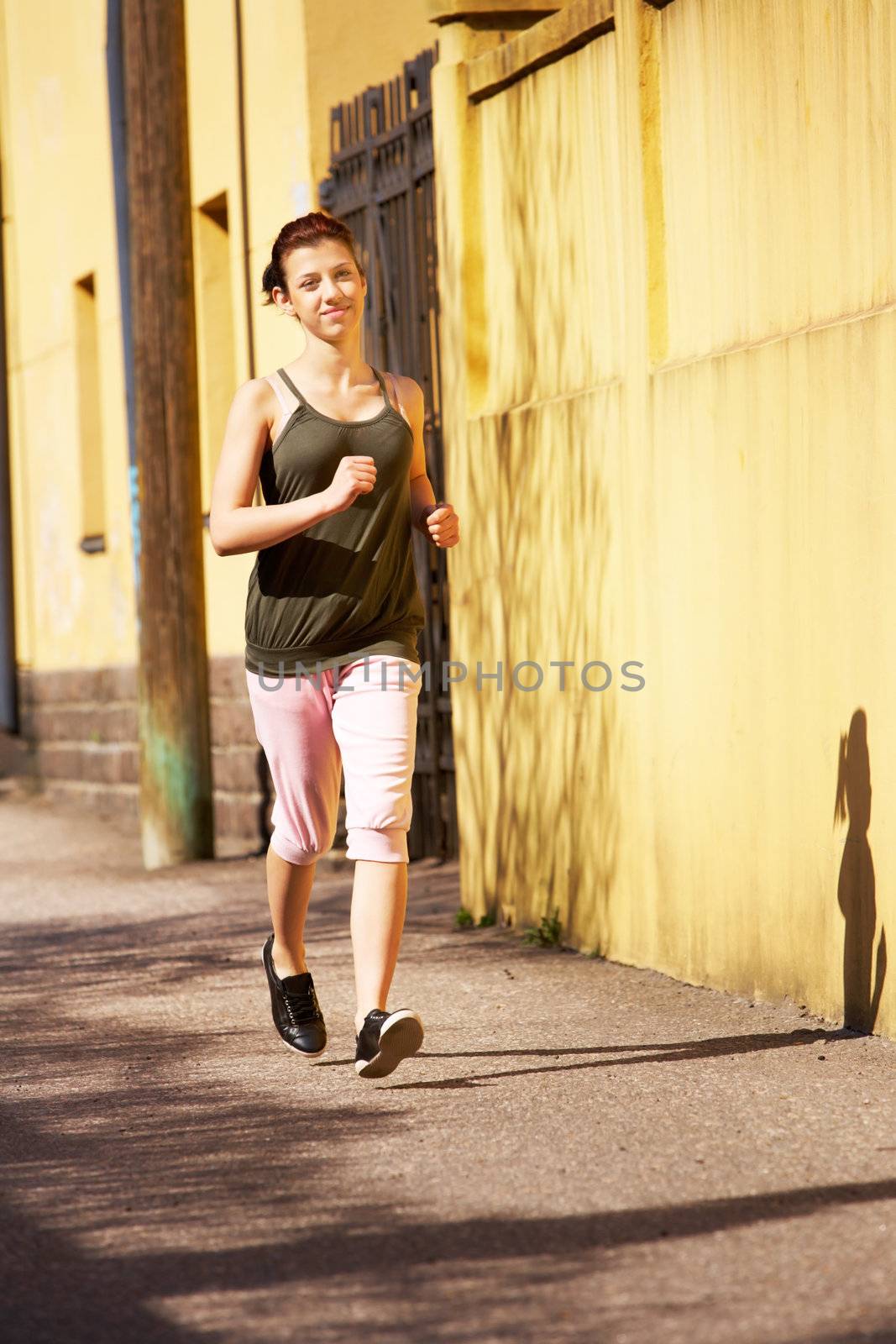 Teenage girl jogging on sidewalk in city