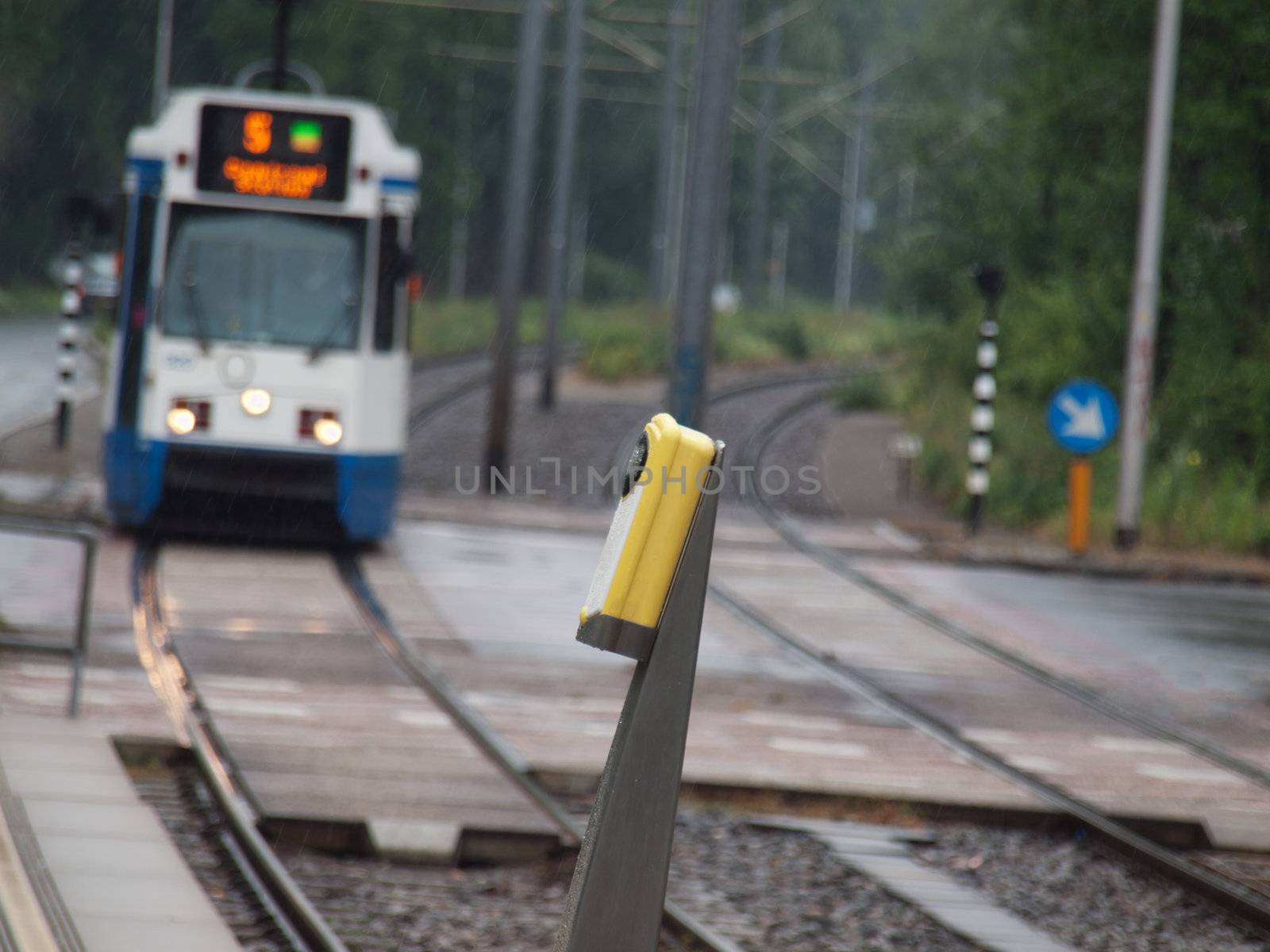 Tramway approaching station in Amsterdam in the Netherlands with pedestrians crossing