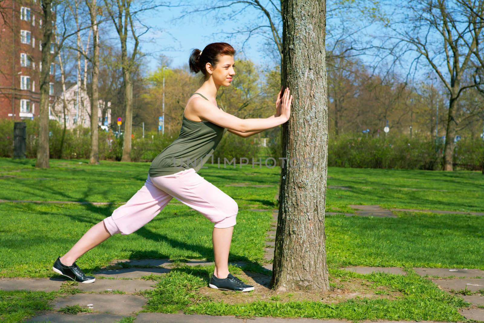 Teenage girl stretching in city park in spring