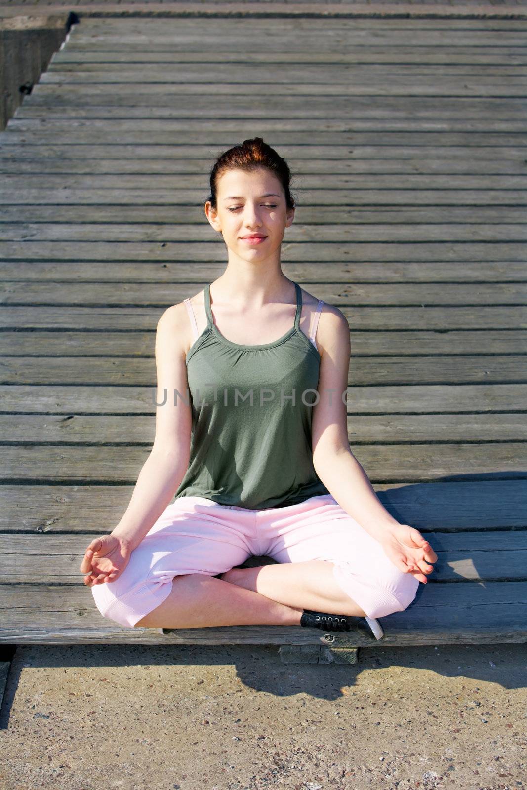 Teenage girl meditating on pier outdoors eyes closed