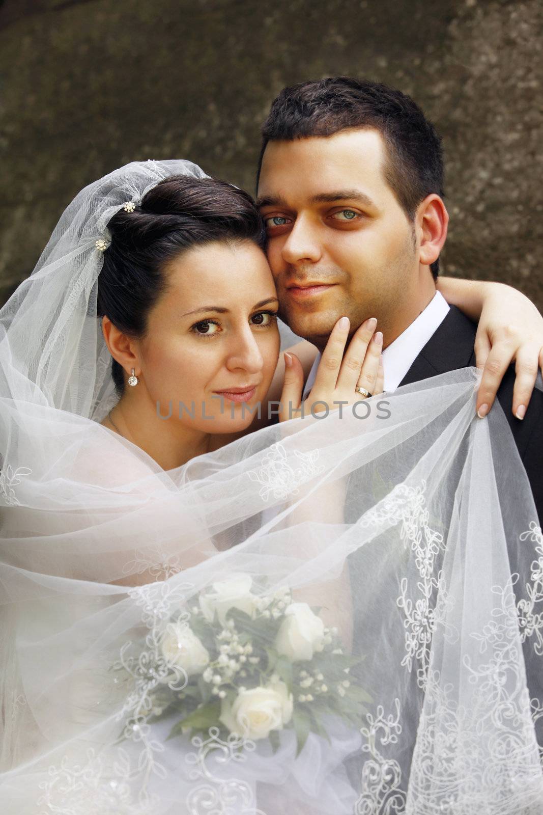 Newly-married couple in wedding clothes in park