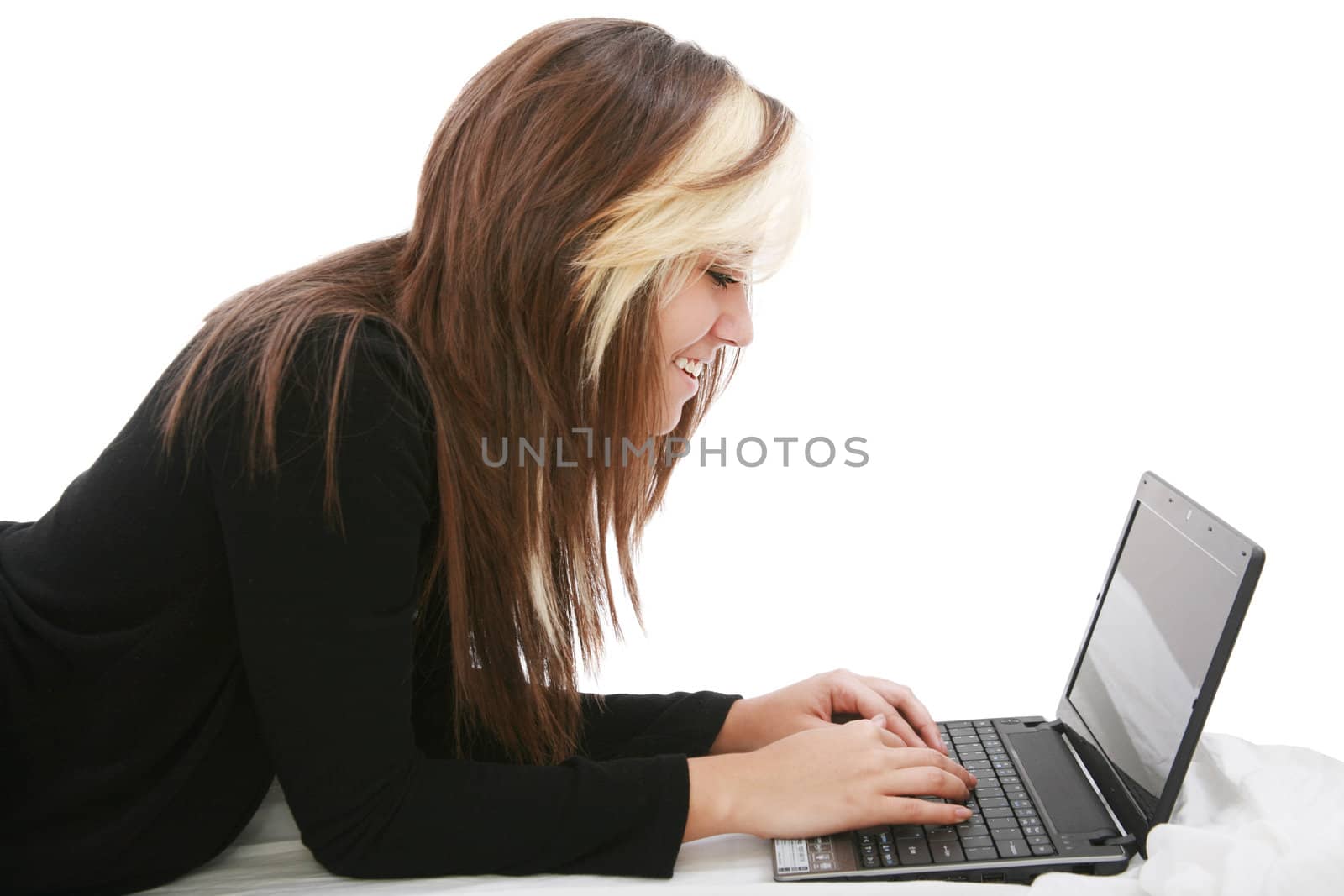 Beautiful girl relaxing on the bed with her laptop
