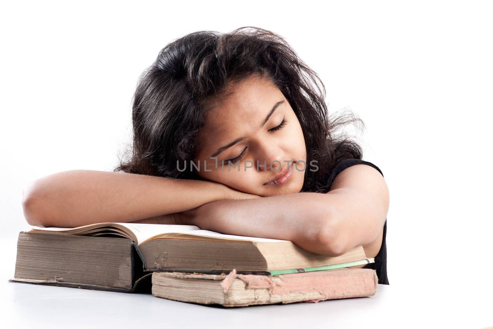 Tired Young indian girl leaned over pile of books, isolated on white