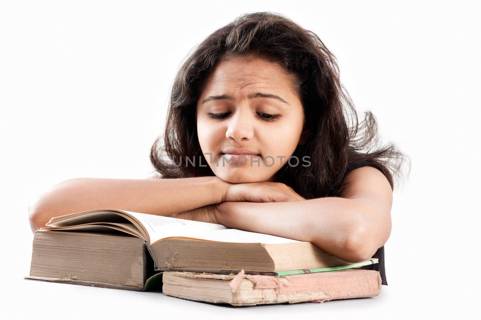 Tired and exhausted Young indian girl leaned over pile of  old books, isolated on white