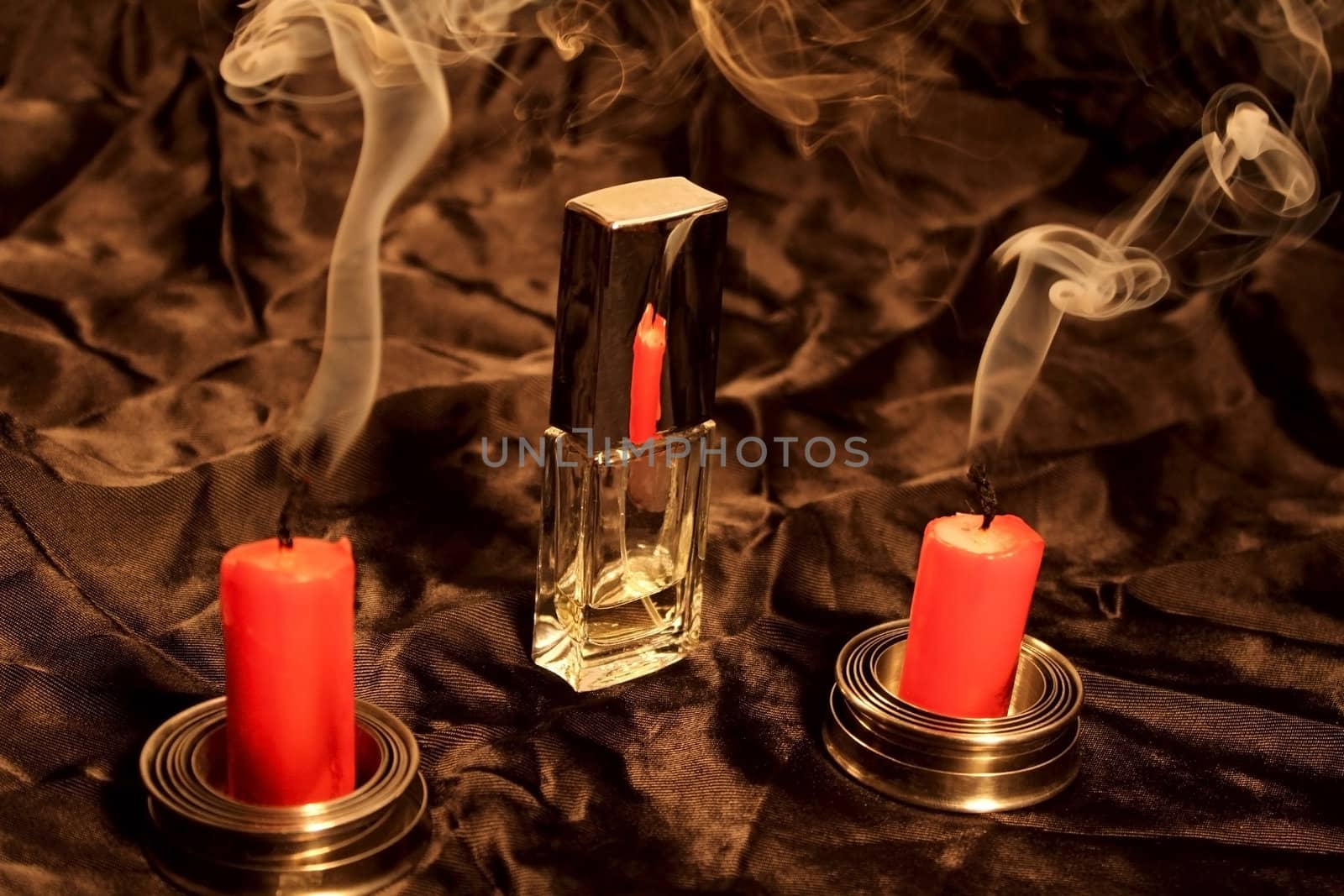 two candles reflex on bottle of perfume