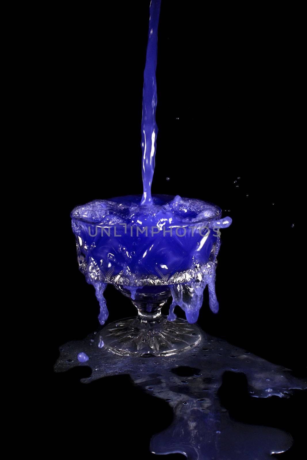 a crystal vase with blue liquid on the black background