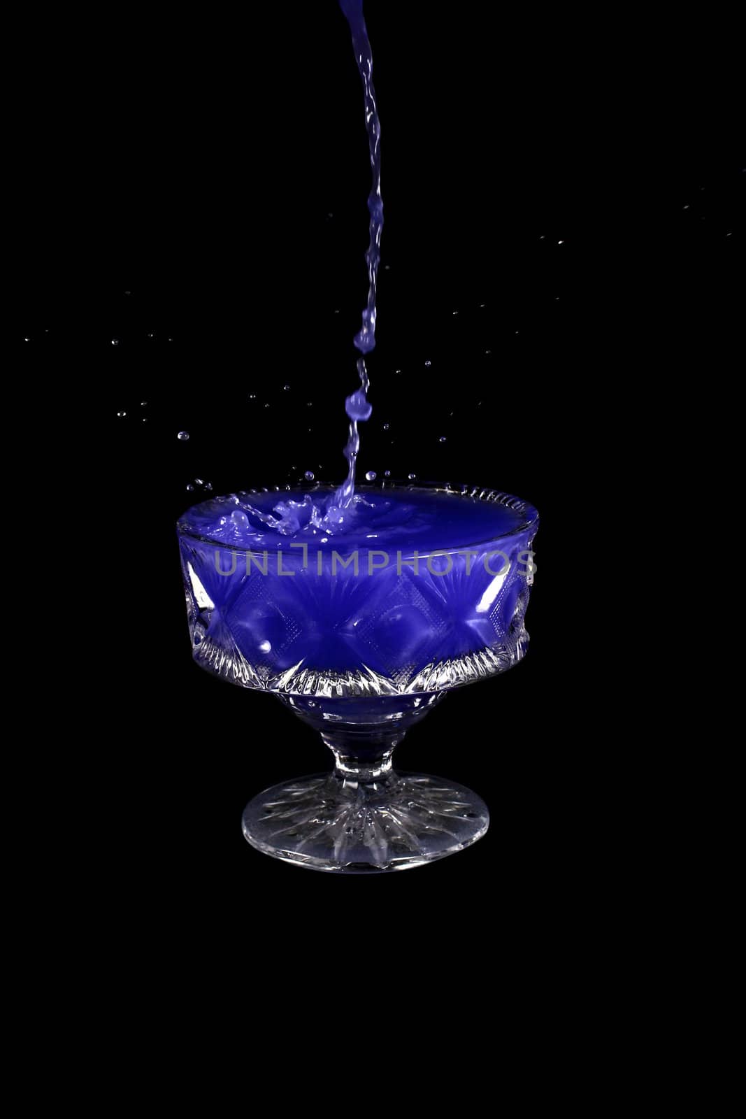 a crystal vase with blue liquid on the black background