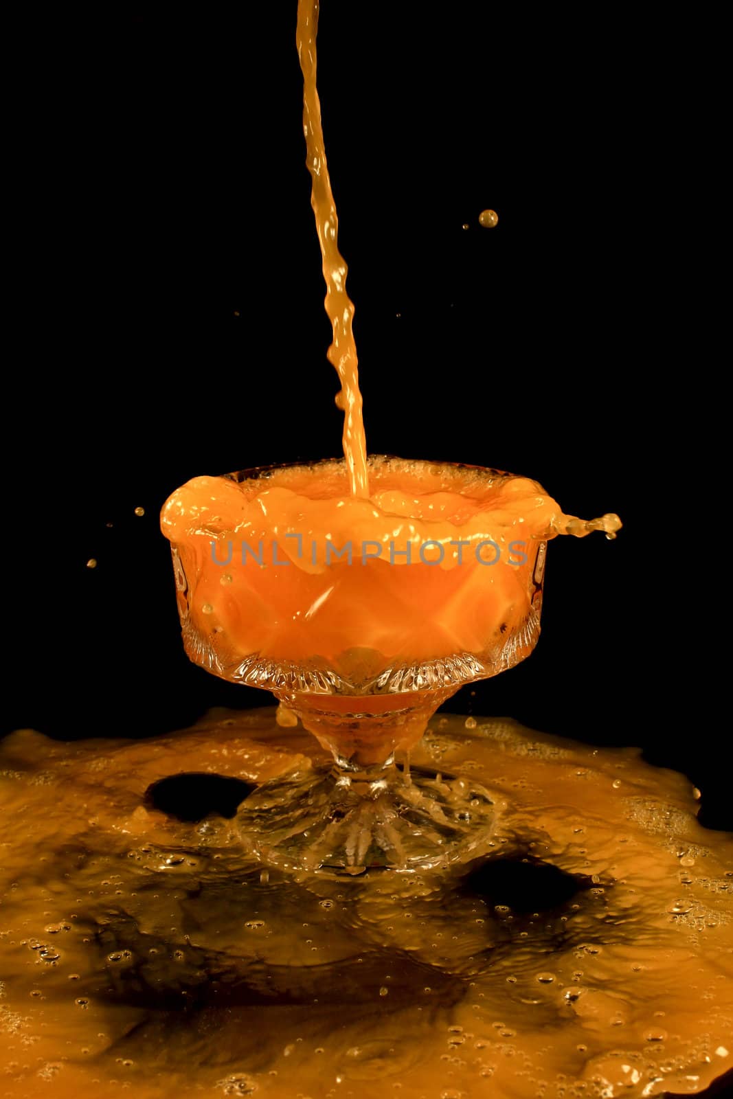 a crystal vase with orange liquid on the black background