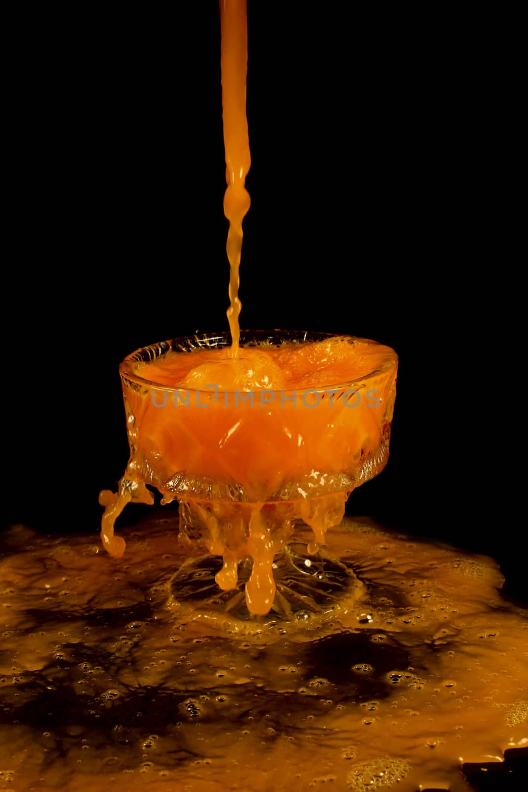 a crystal vase with orange liquid on the black background