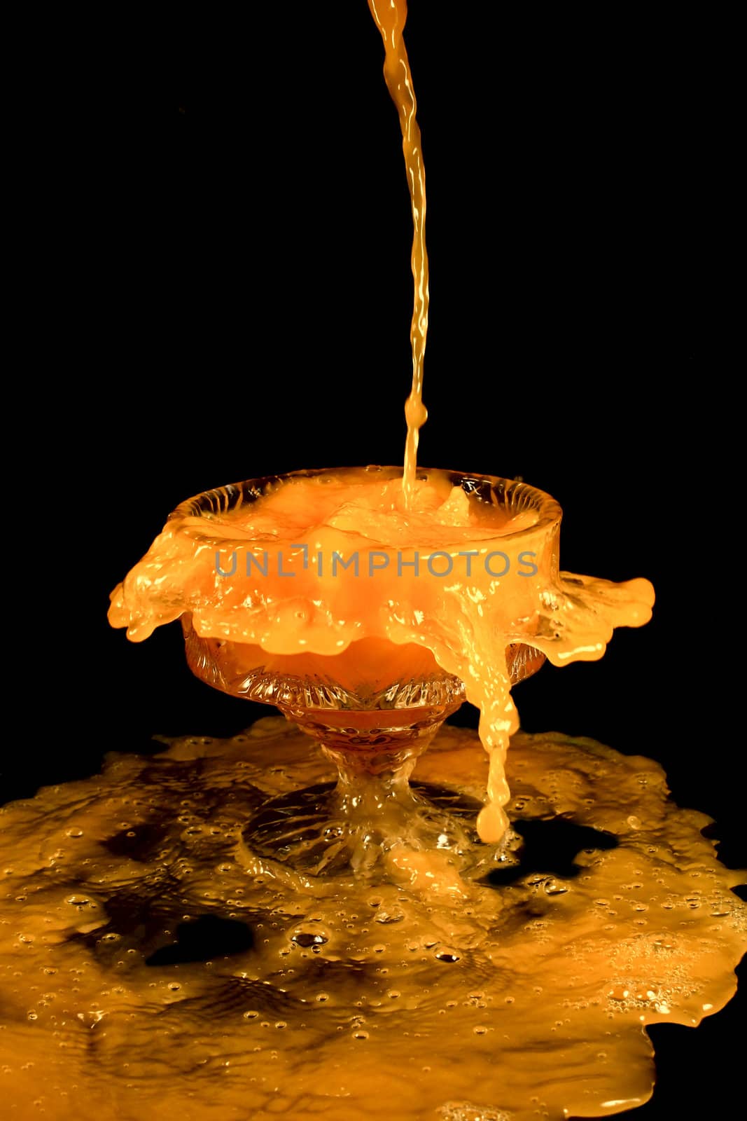 a crystal vase with orange liquid on the black background