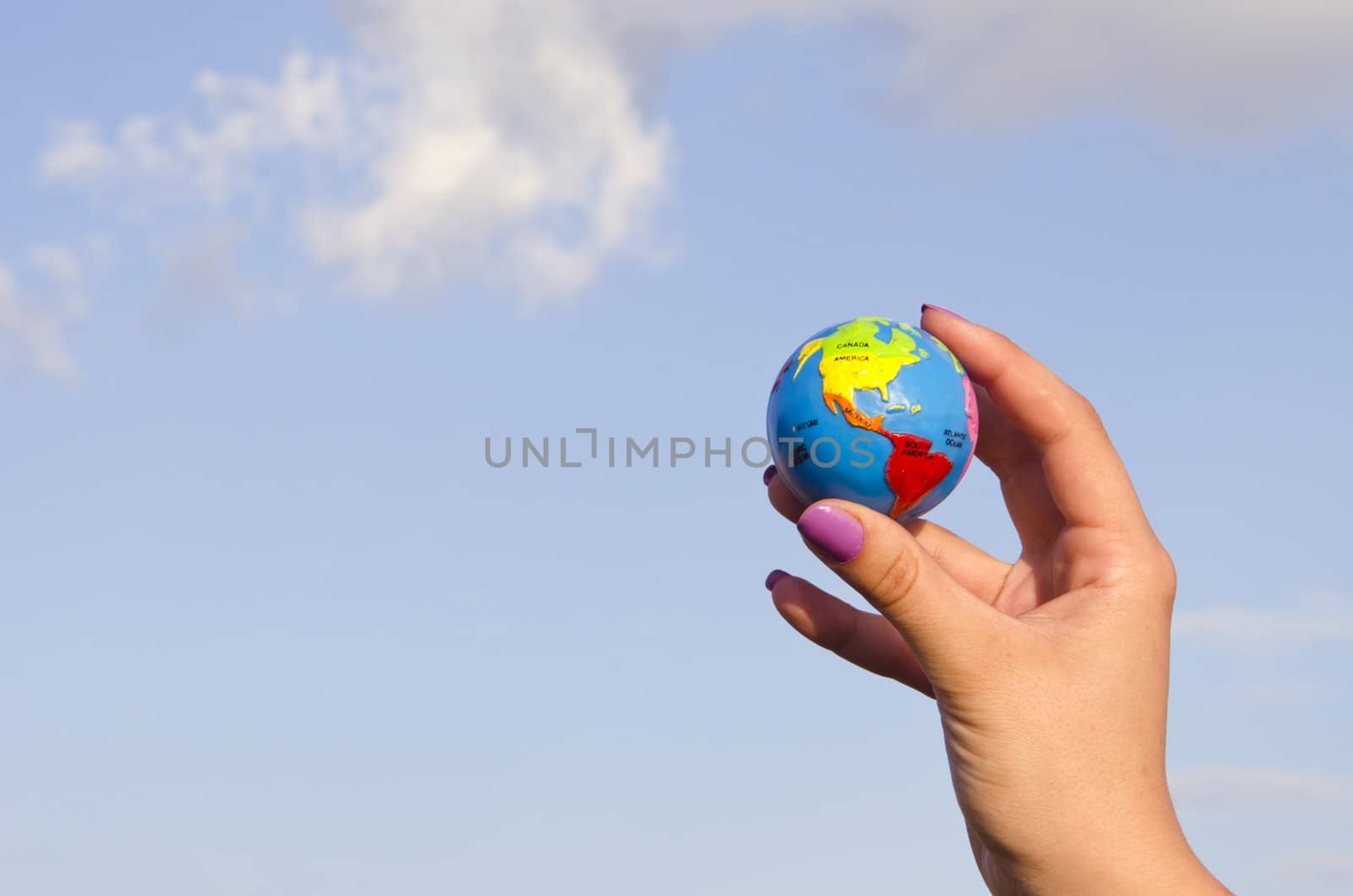 Hand of a woman with colored nails hold earth circle globe.