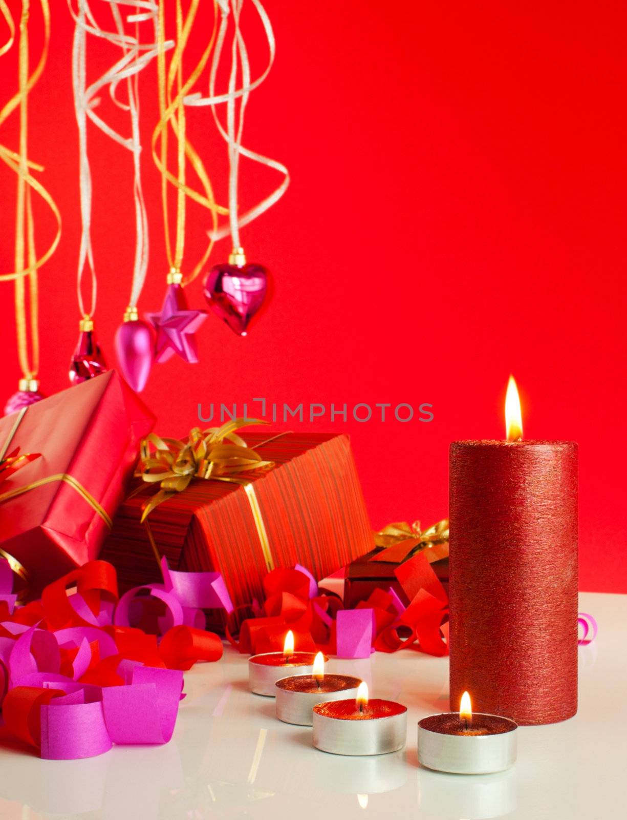 Christmas gifts and candles over red background