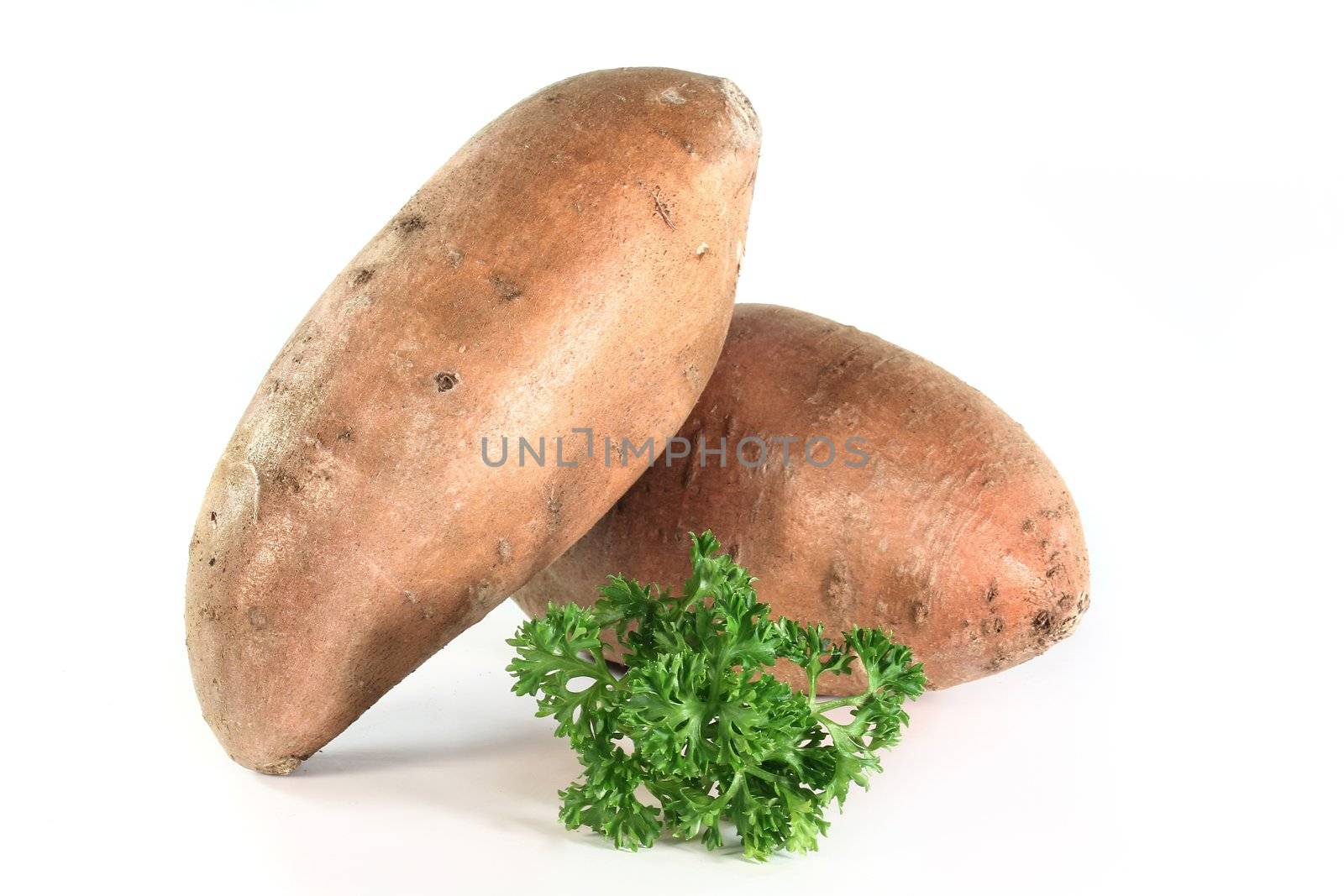 two sweet potatoes and parsley on a white background