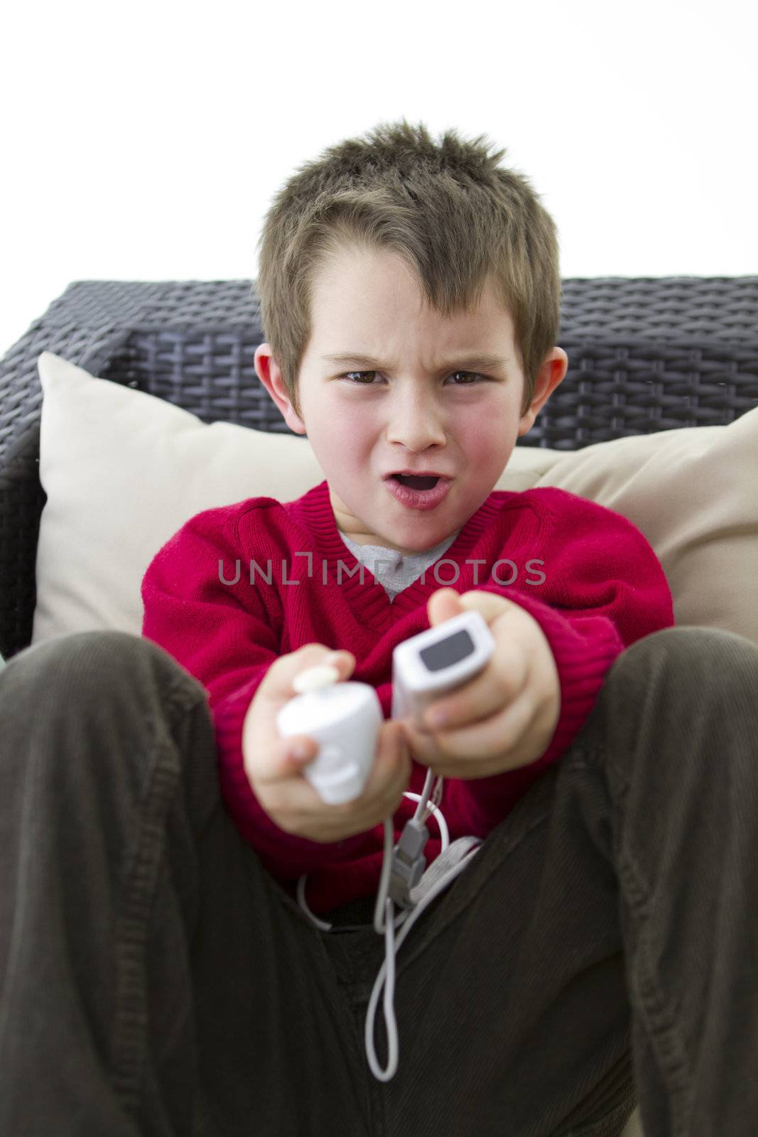 A white male caucasian 6 years old kid playing video game on the cauch.