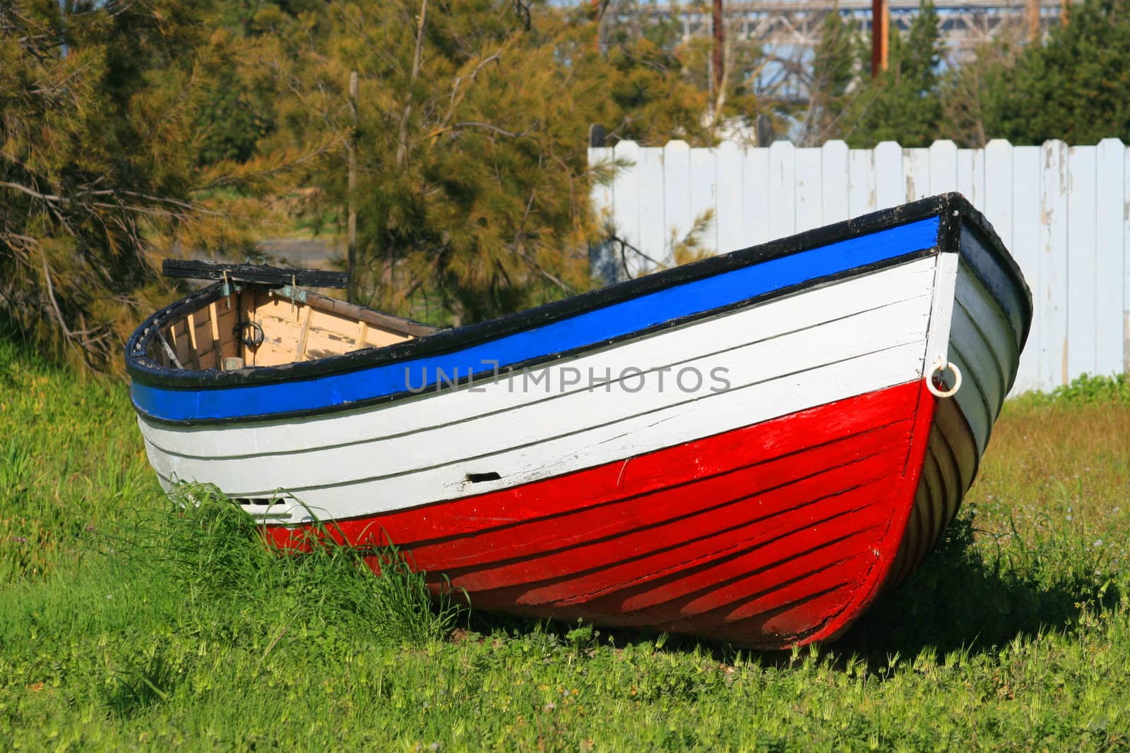 Old three color wooden boat on a grass.
