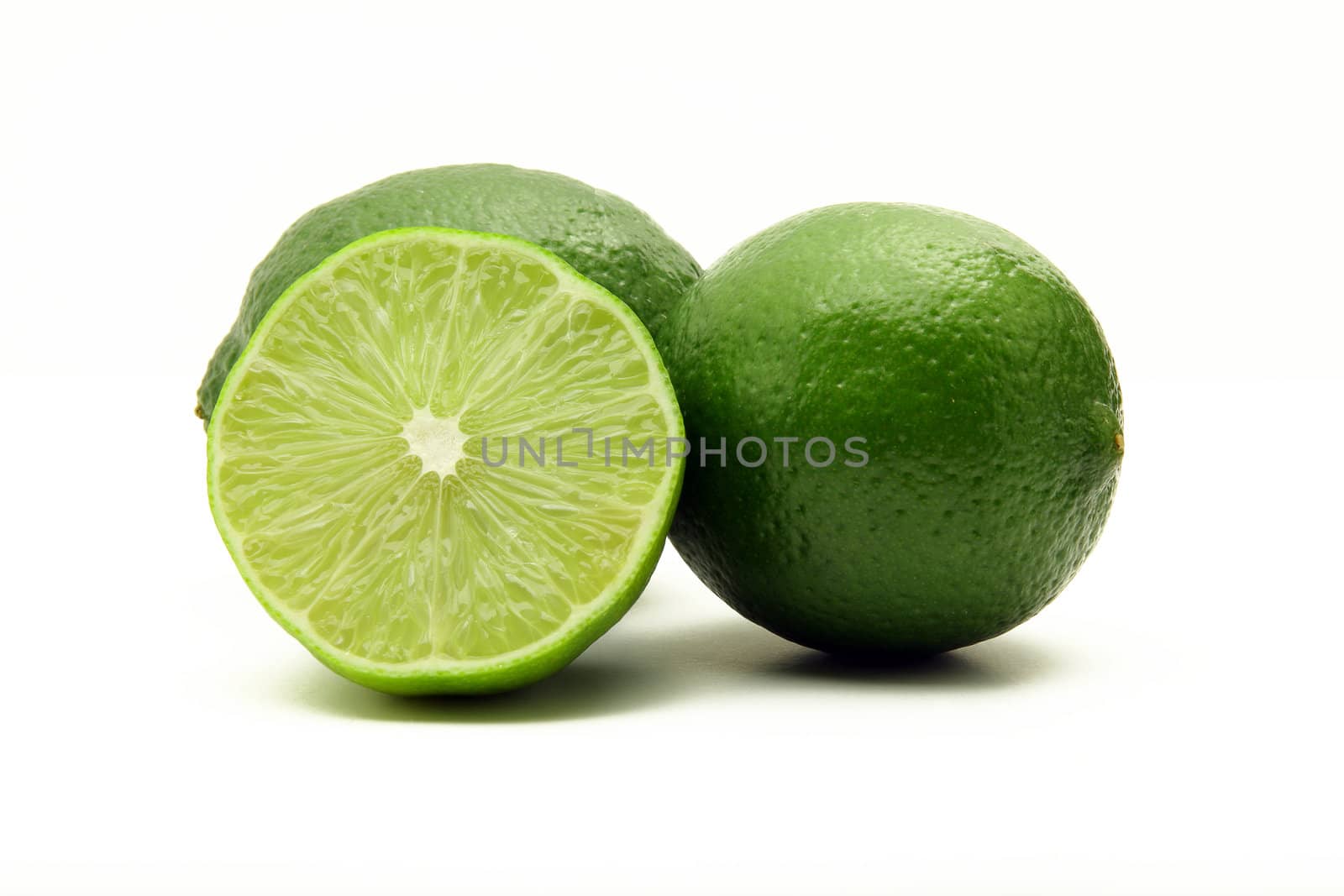 Three green juicy limes isolated on white background, one cut in half