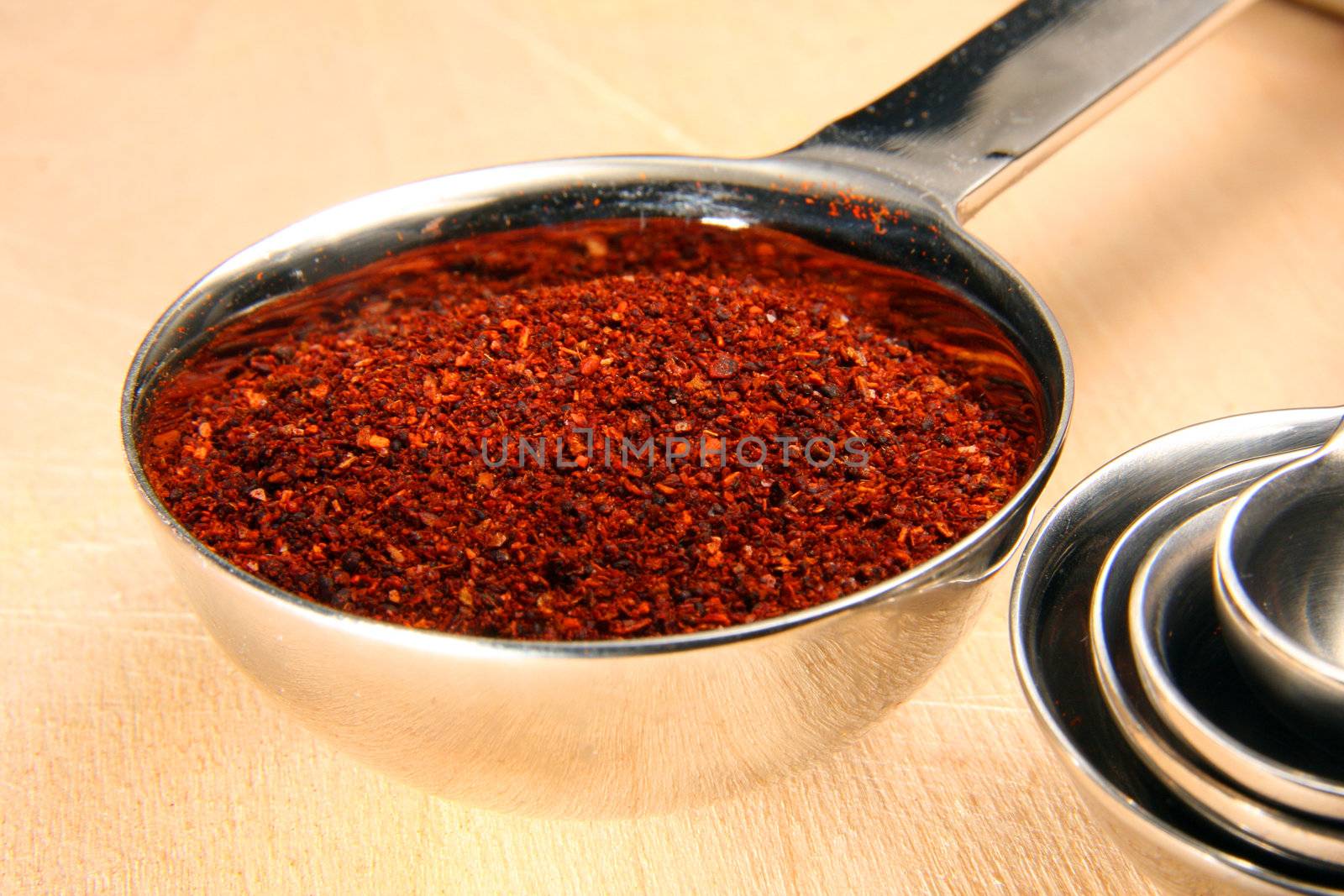 Chili powder in measuring spoon on cutting board