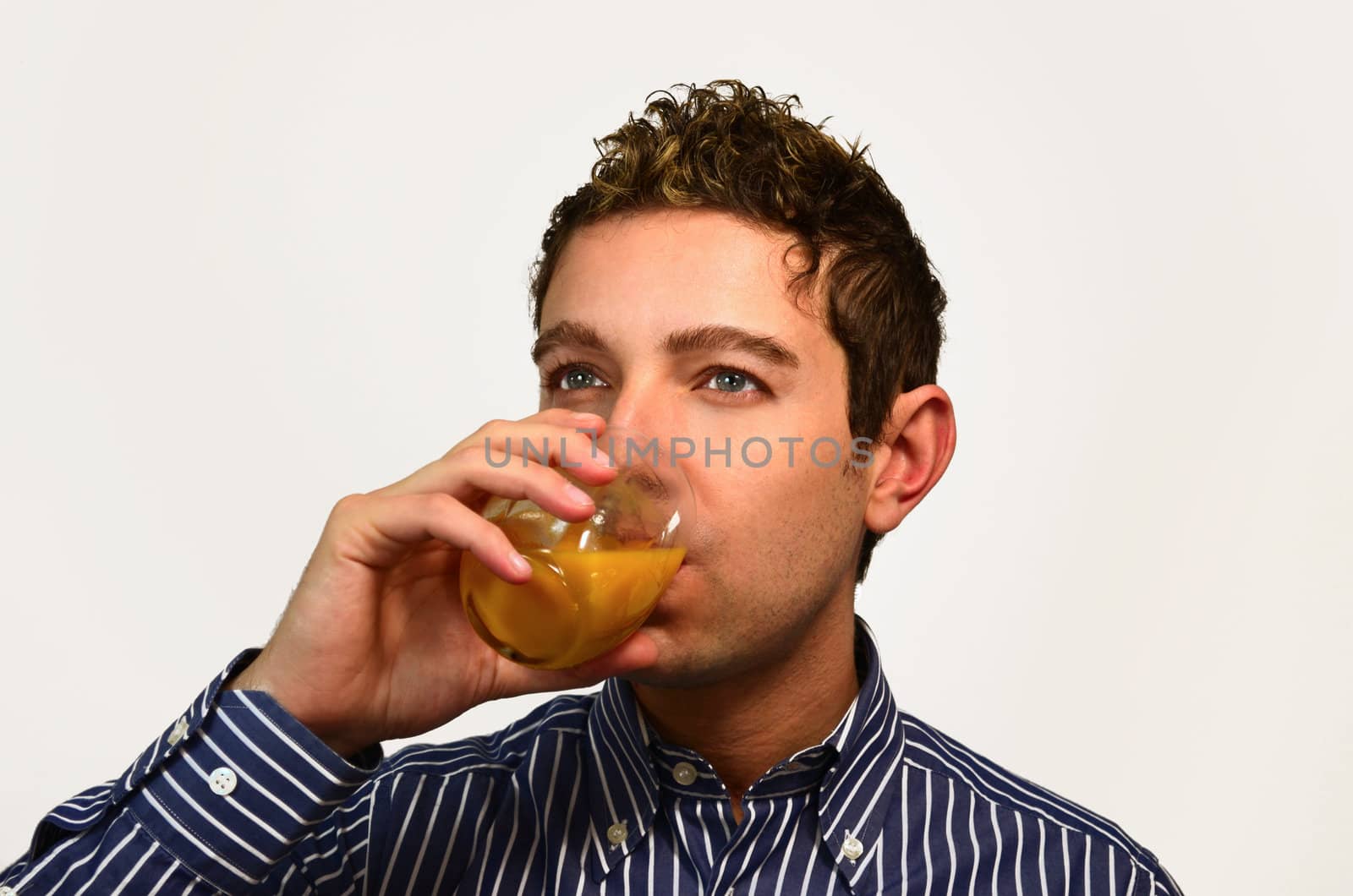 Good looking guy drinking fruit juice from a glass, isolated on white