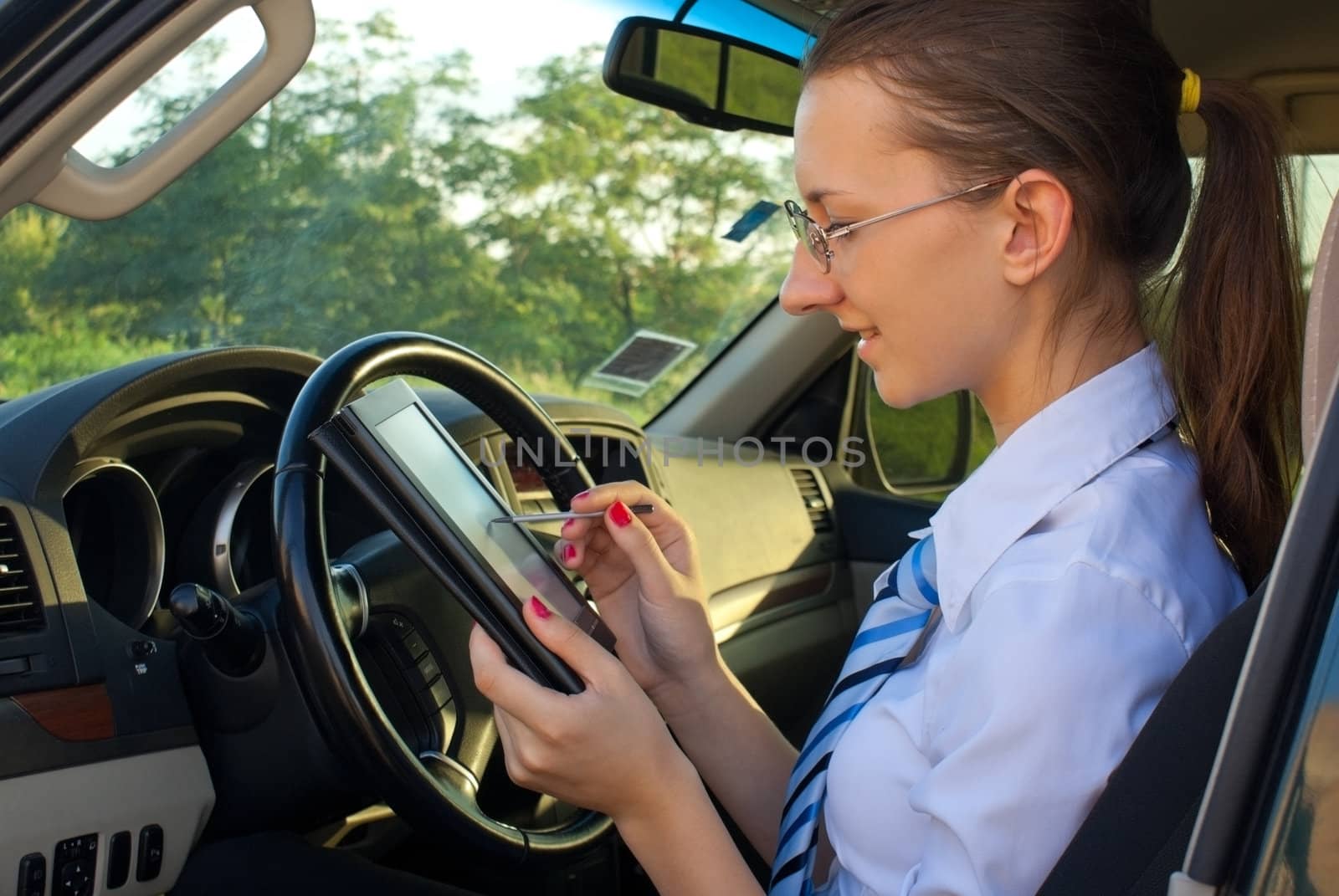 Young lady reads electronic book sitting in the car by AndreyKr