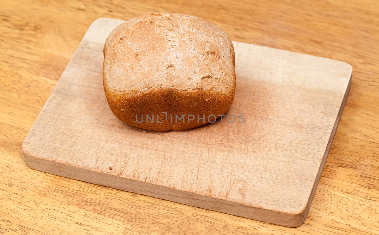 Whole wheat loaf from a bread making machine ready to cut on cutting board