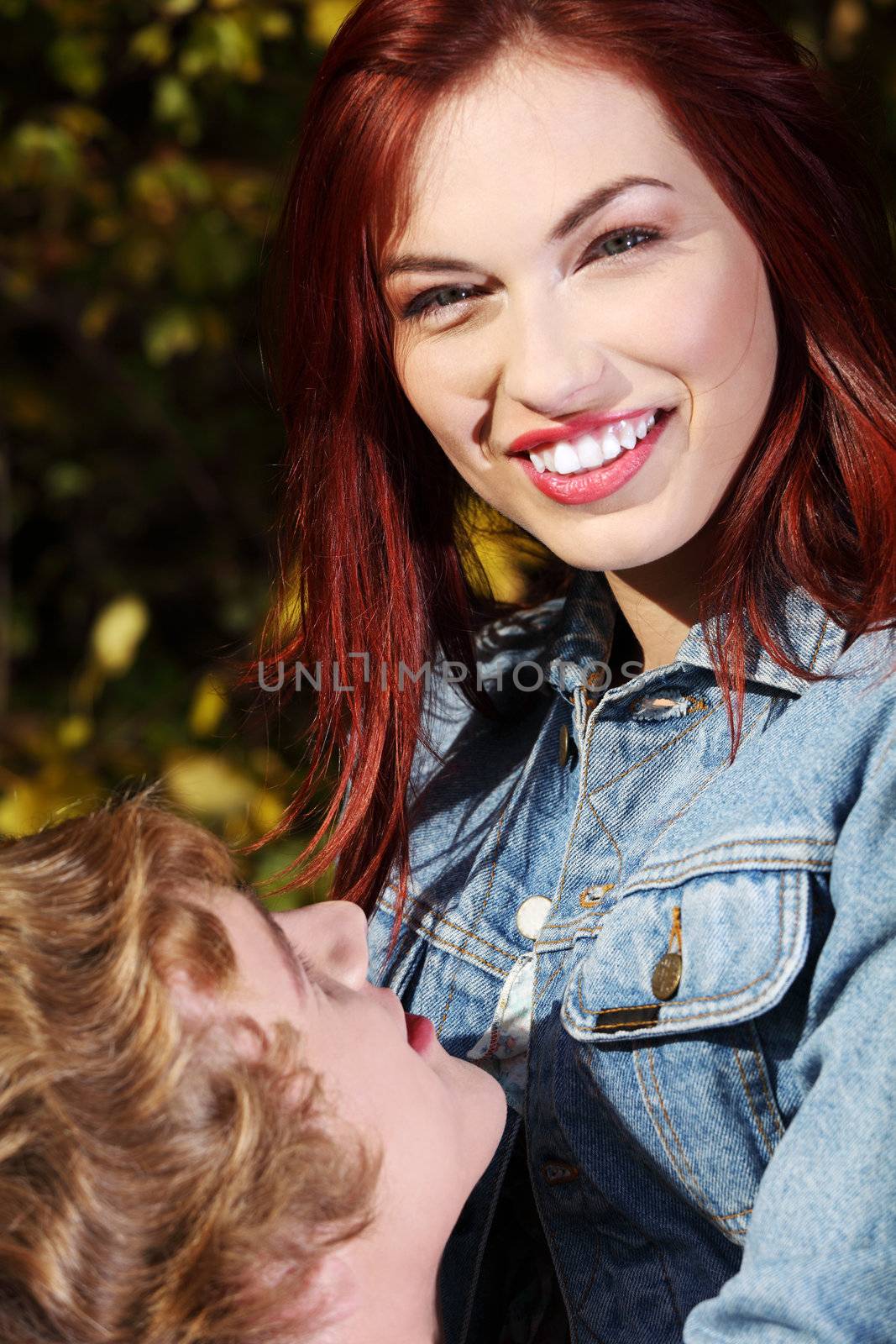 Happy smiling caucasian girl embraceable by her boyfriend - outdoor.