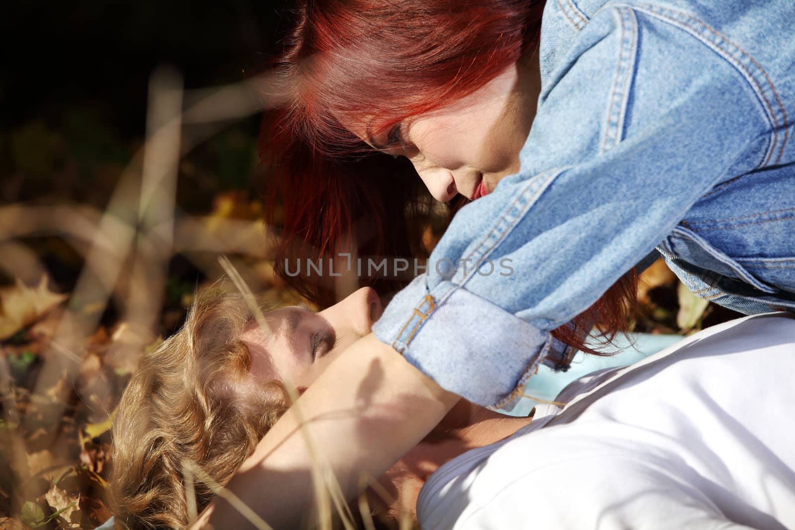 Young caucasian couple lying on meadow and looking at each other.