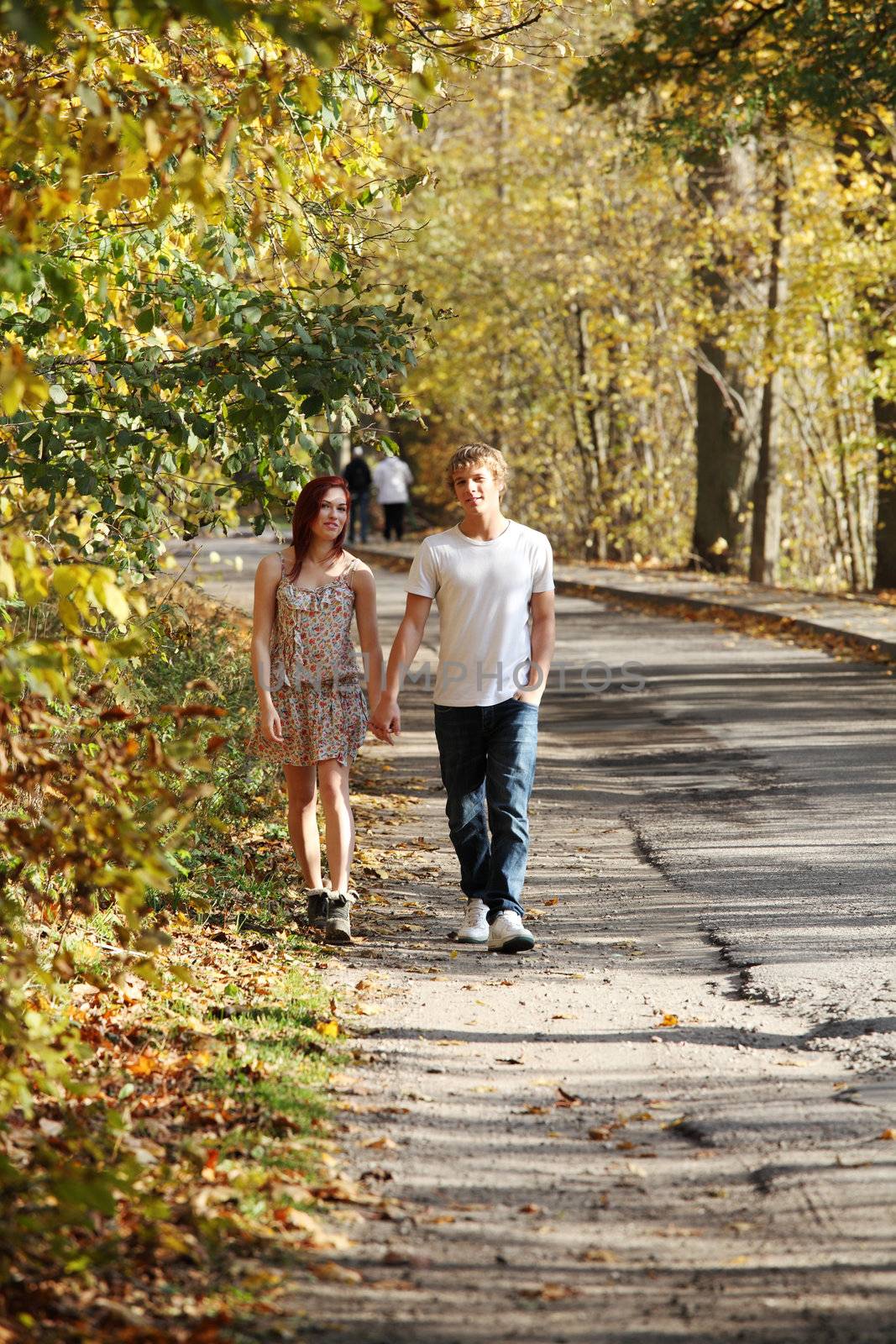 Young caucasian couple walking hand by hand in the park.