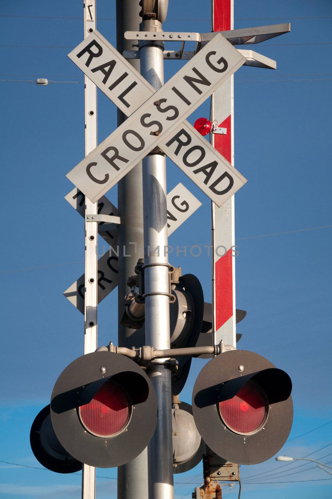 Stop lights at rail crossing under bright blue sky