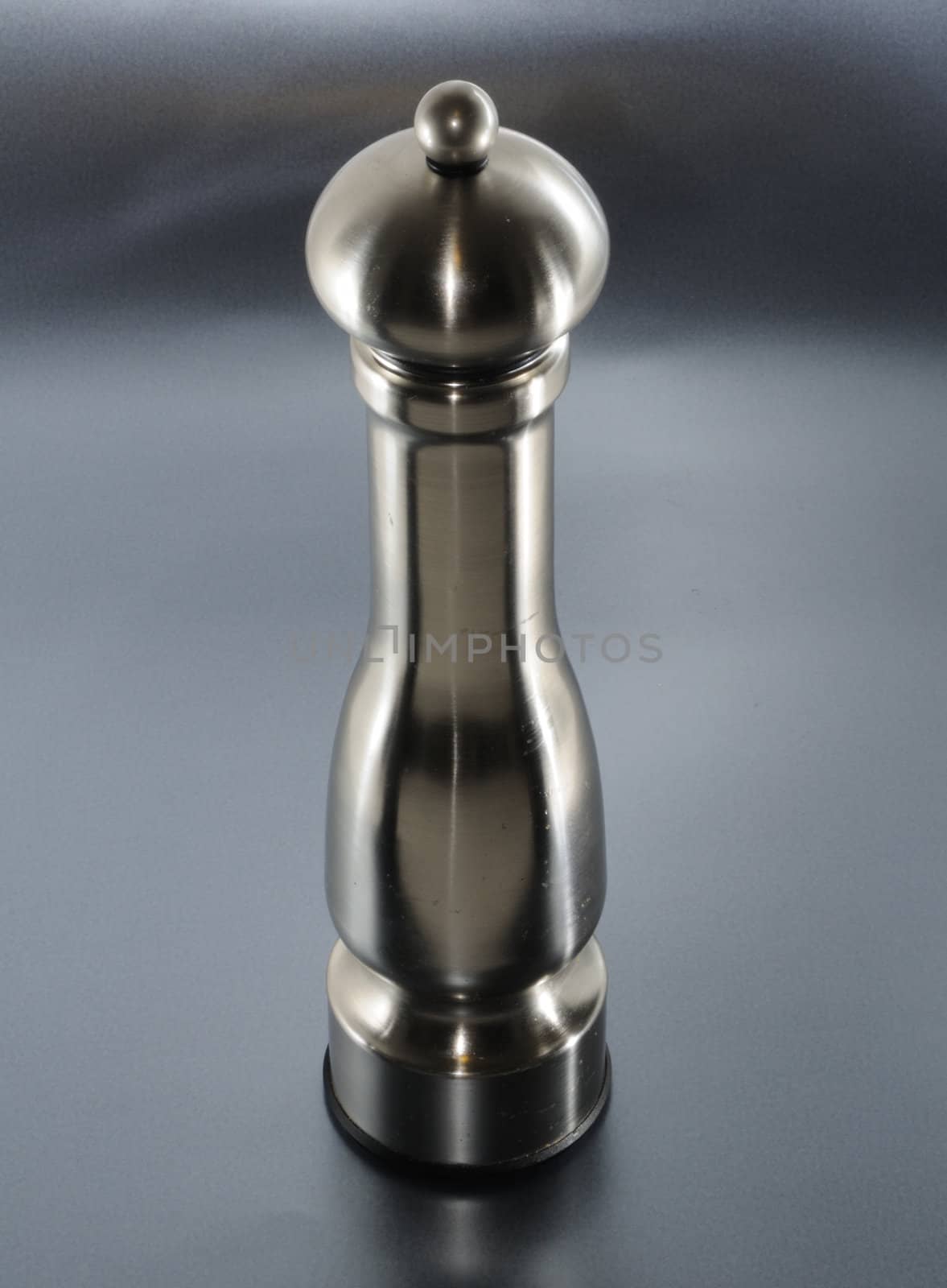 Metal pepper mill over silver background