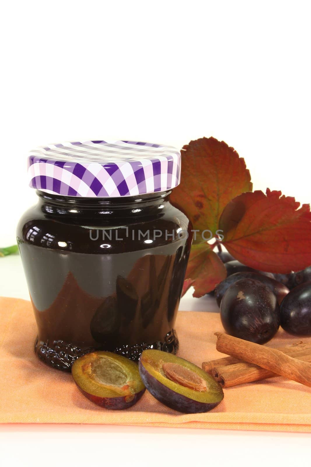a glass of plum jam with autumnal decorations