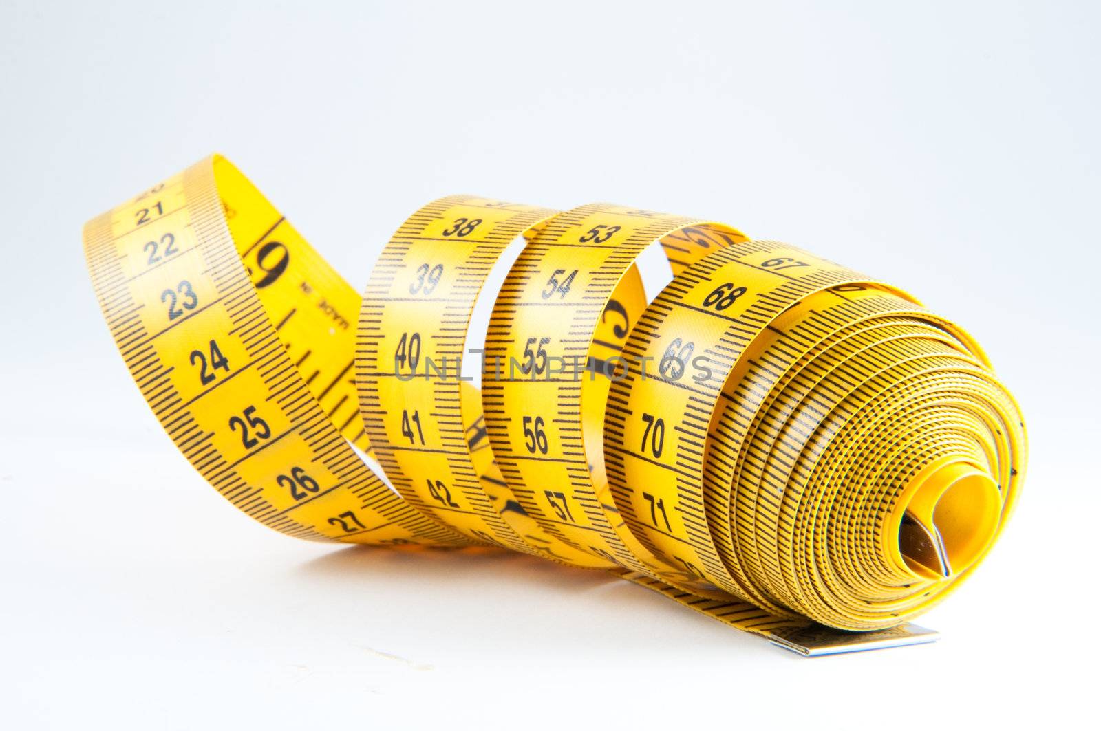 Roll of yellow measuring tape rolled up over white background