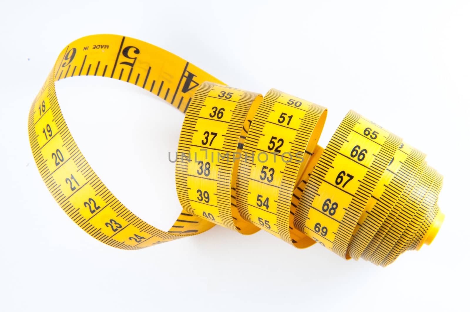 Roll of yellow measuring tape rolled up over white background