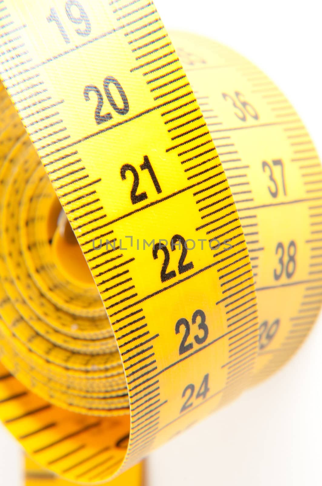 Roll of yellow measuring tape rolled up over white background