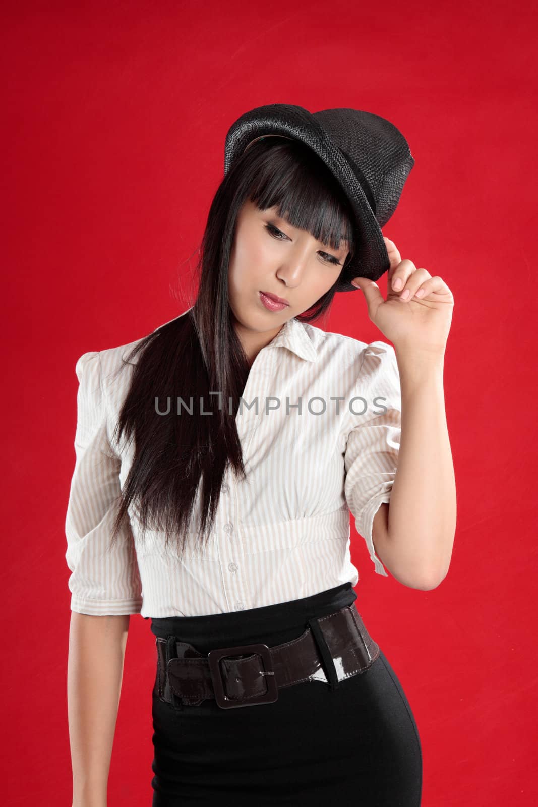 Young mixed race woman looking down.  She is wearing a hat and is tilting her head slightly.