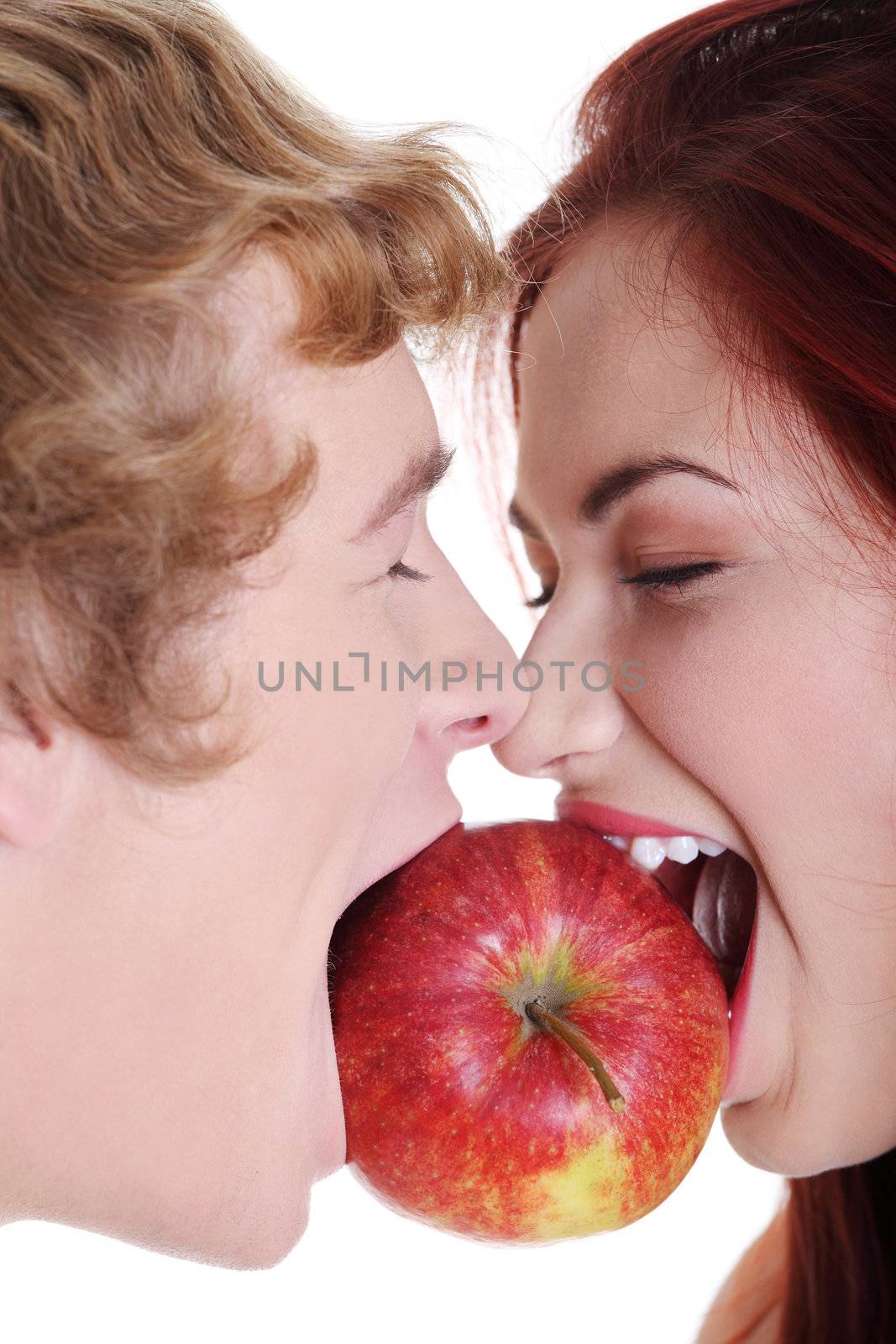 Closeup of young caucasian coupe biting apple over against white background.