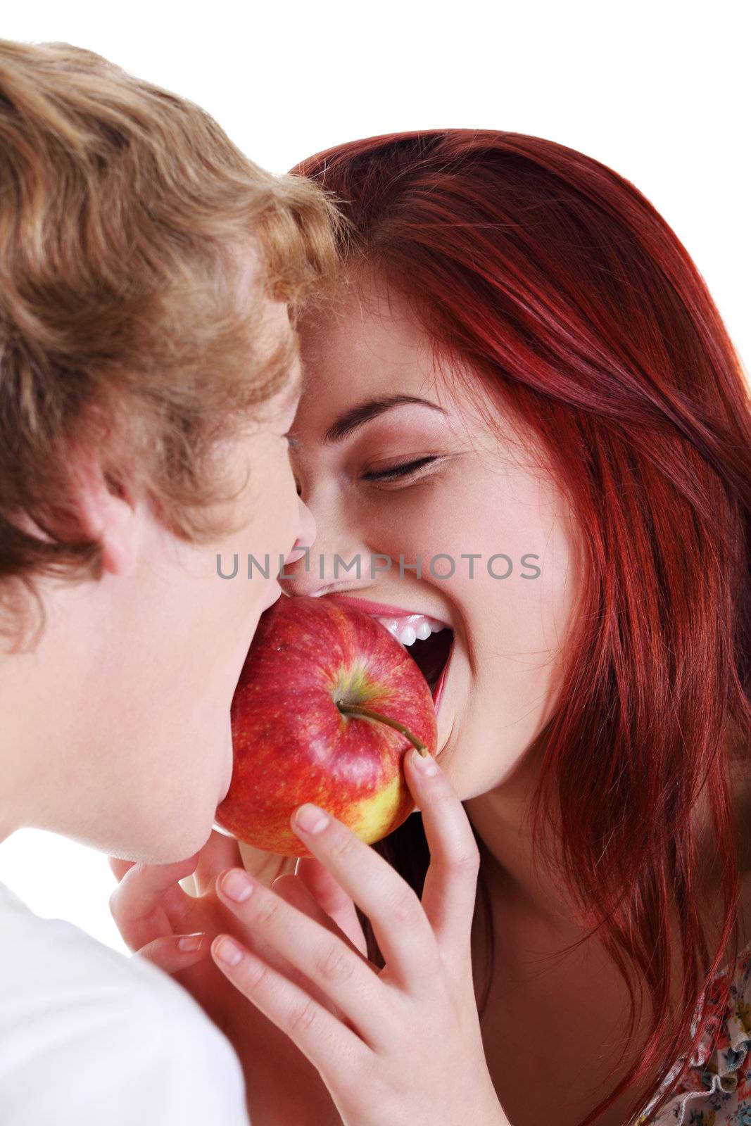 Young caucasian couple biting red apple over white background