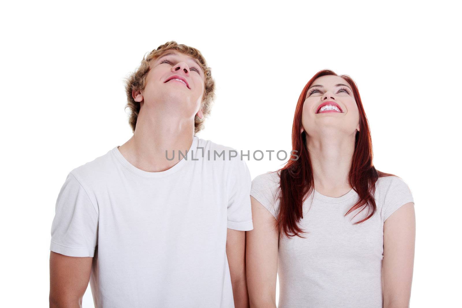 Young caucasian couple looking up against white background.