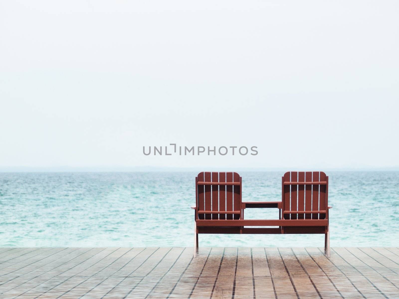 Two empty chair at a resort facing the south China sea in Pulau Besar Malaysia with a boat in the background