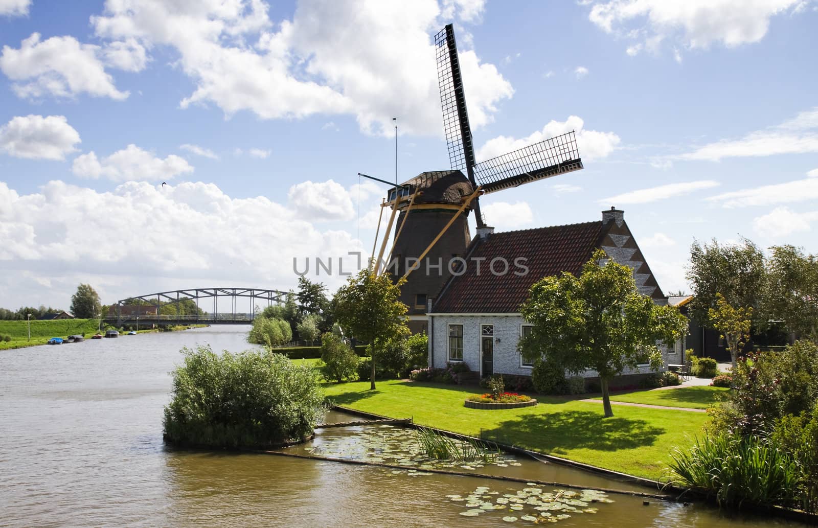 Typical Dutch landscape -  windmill, house and bridge at the waterside