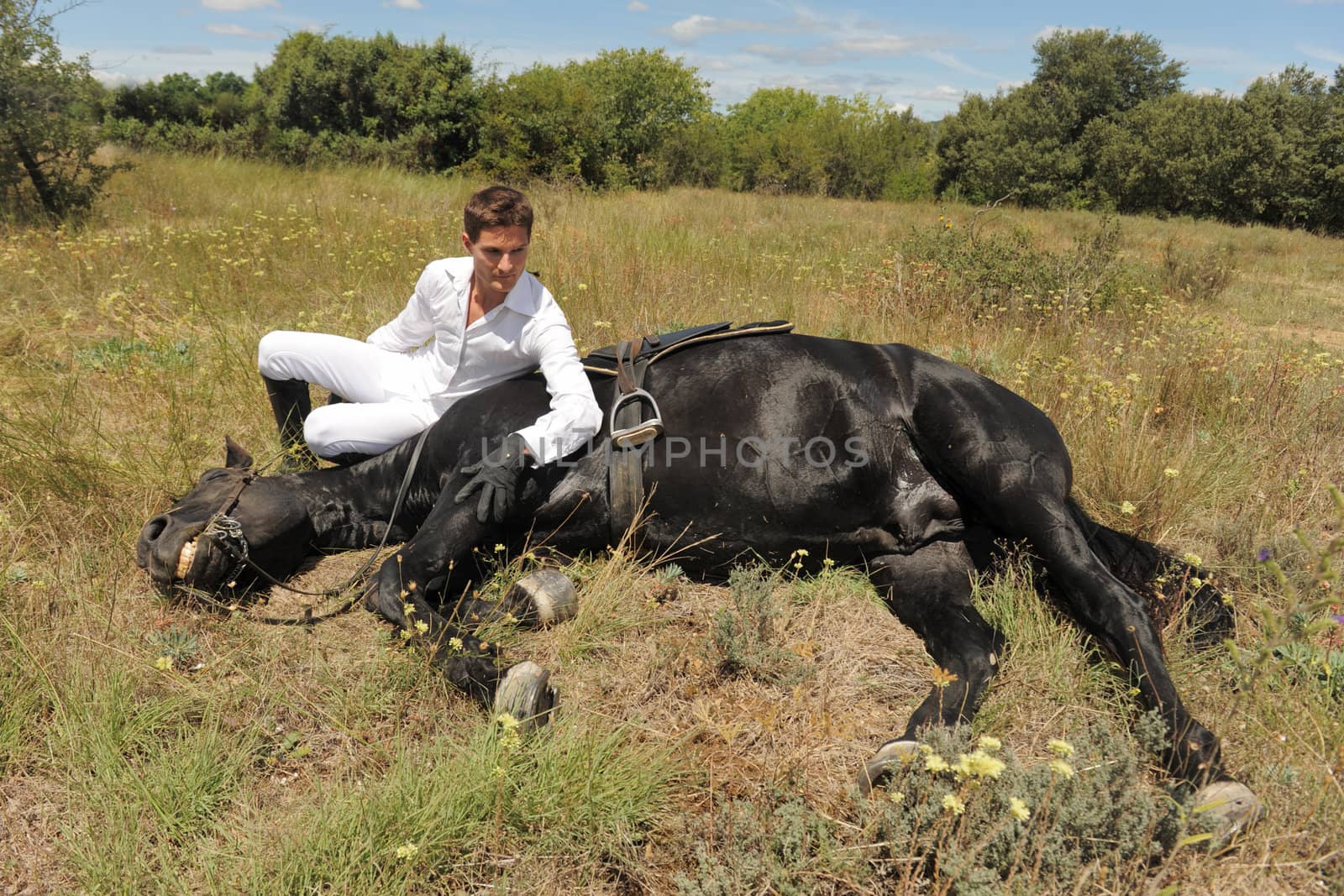 young man and his black stallion in  a field