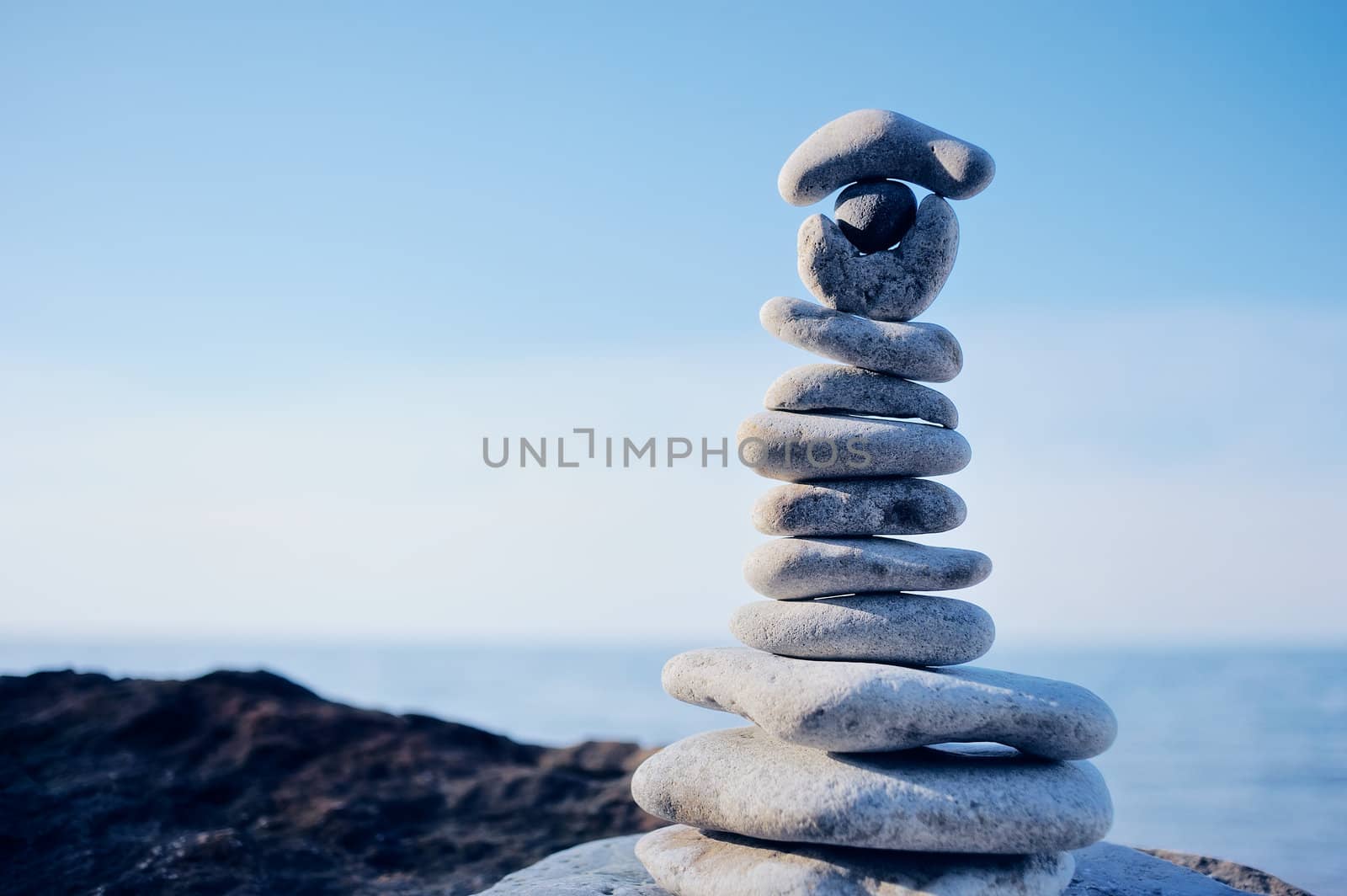 Balancing white pebbles each other on a sea boulder