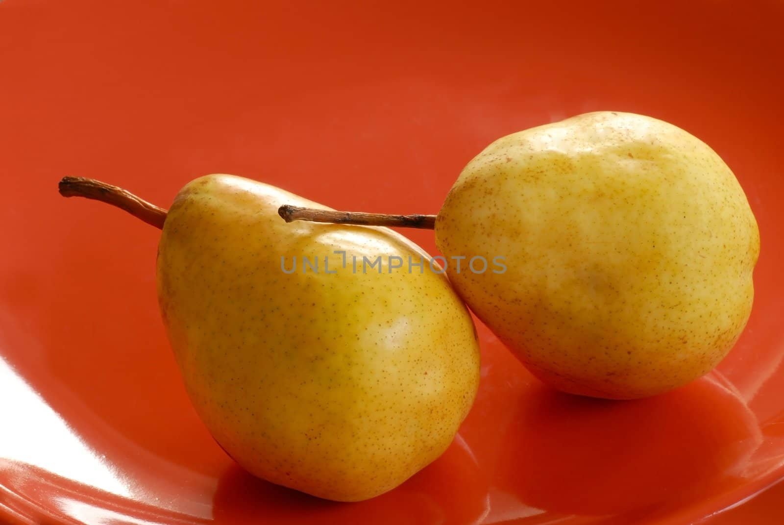 two appetizing yellow pears on red plate