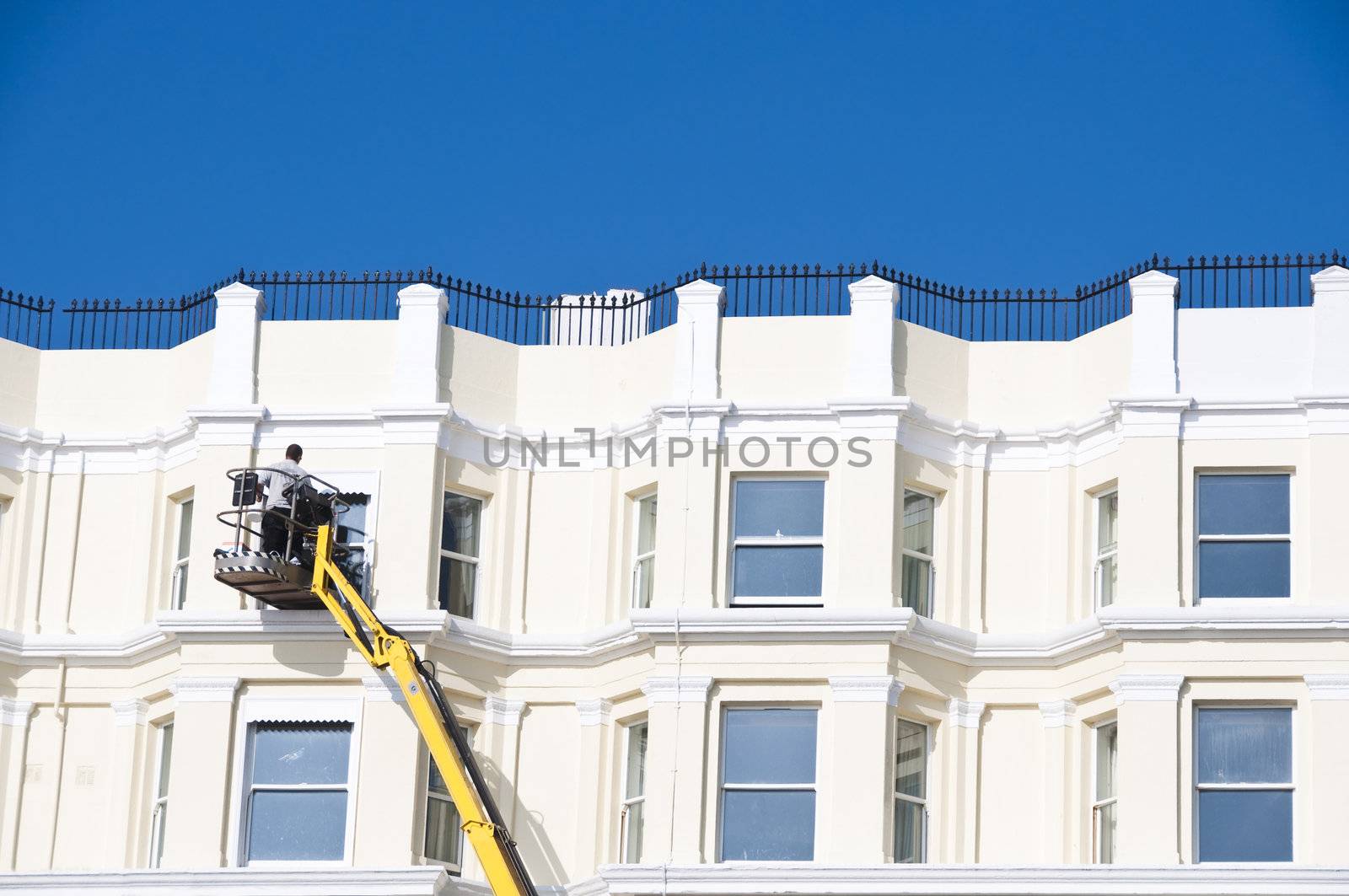 A man cleaning sash windows from outside in the UK